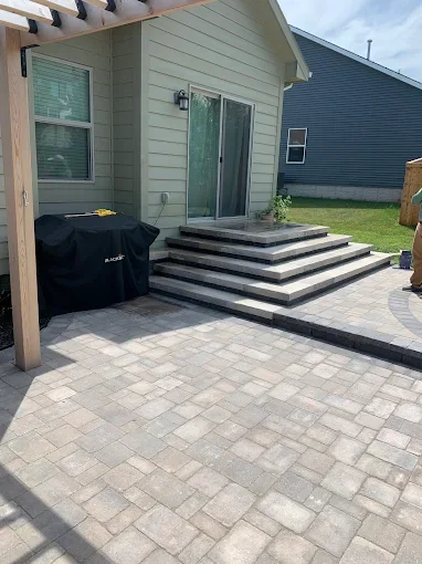 Multi-level hardscape transformation featuring a stunning paver patio and custom-formed paver steps.