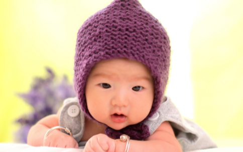kelowna daycare asian infant on tummy wearing purple hat