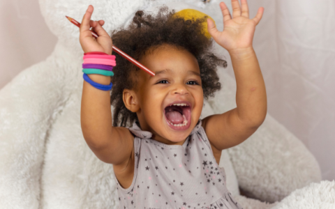kelowna daycare african-american toddler girl smiling with colorful bracelets