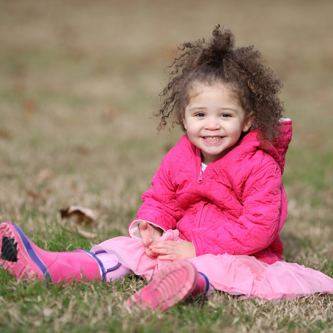 kelowna toddler girl in pink sitting on grass daycare