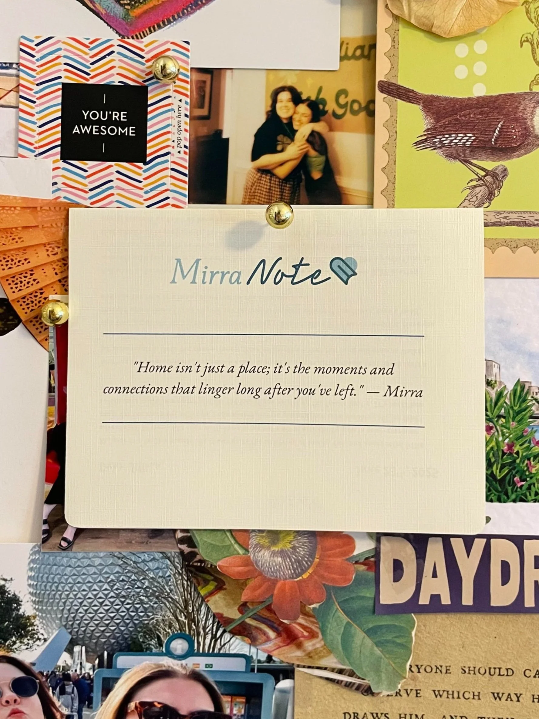 A bulletin board with various photos and notes, including a postcard with a black square that says "You're Awesome," a photo of two women hugging, and a lined note titled 'Mirra Notes' with a quote about home and connections.