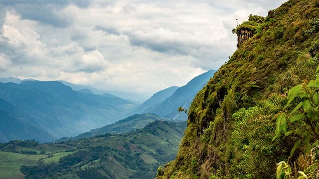 Lush green mountains with a cloudy sky in the background.