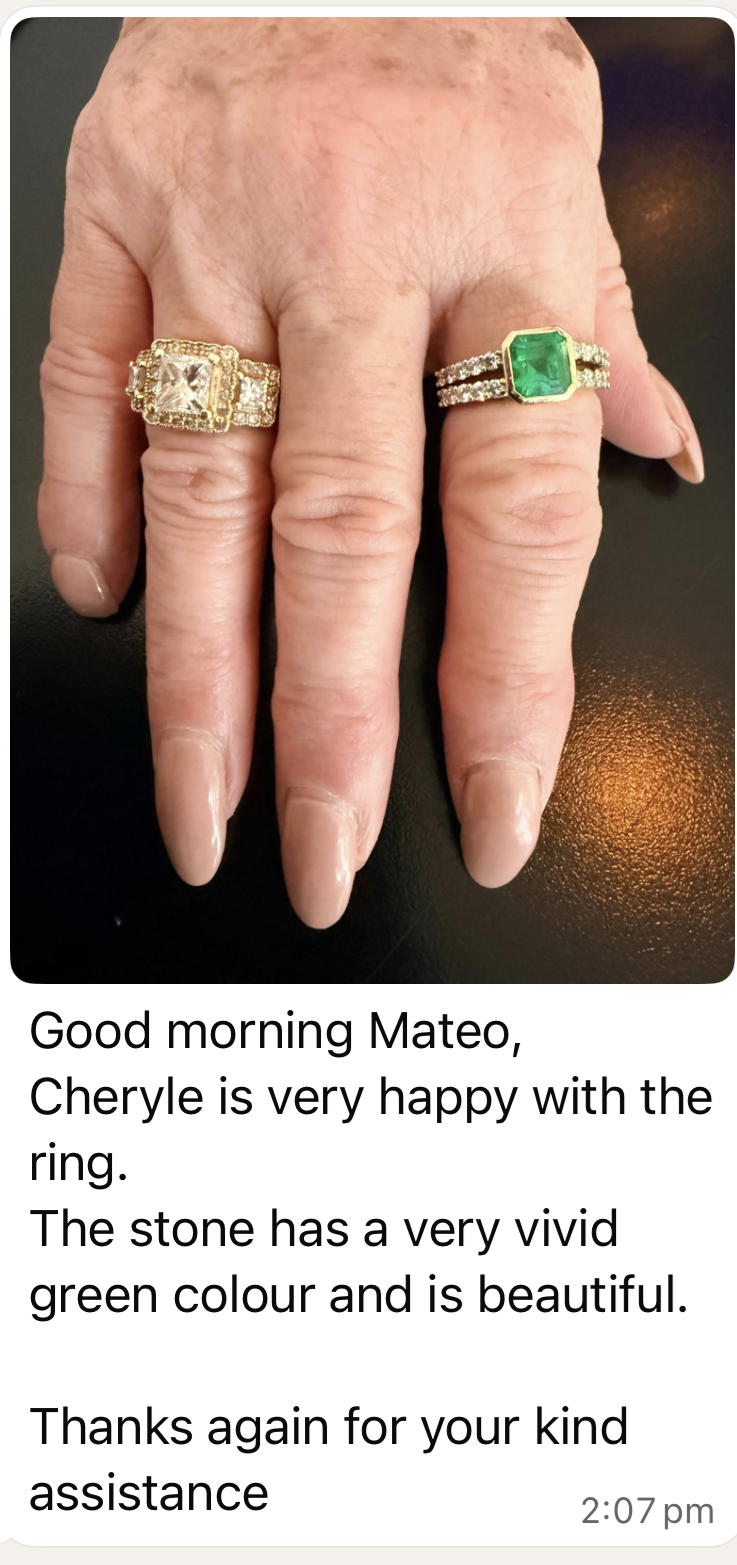 Close-up of a hand with two ornate rings: one with an emerald gemstone and the other with a large clear stone, worn on different fingers.