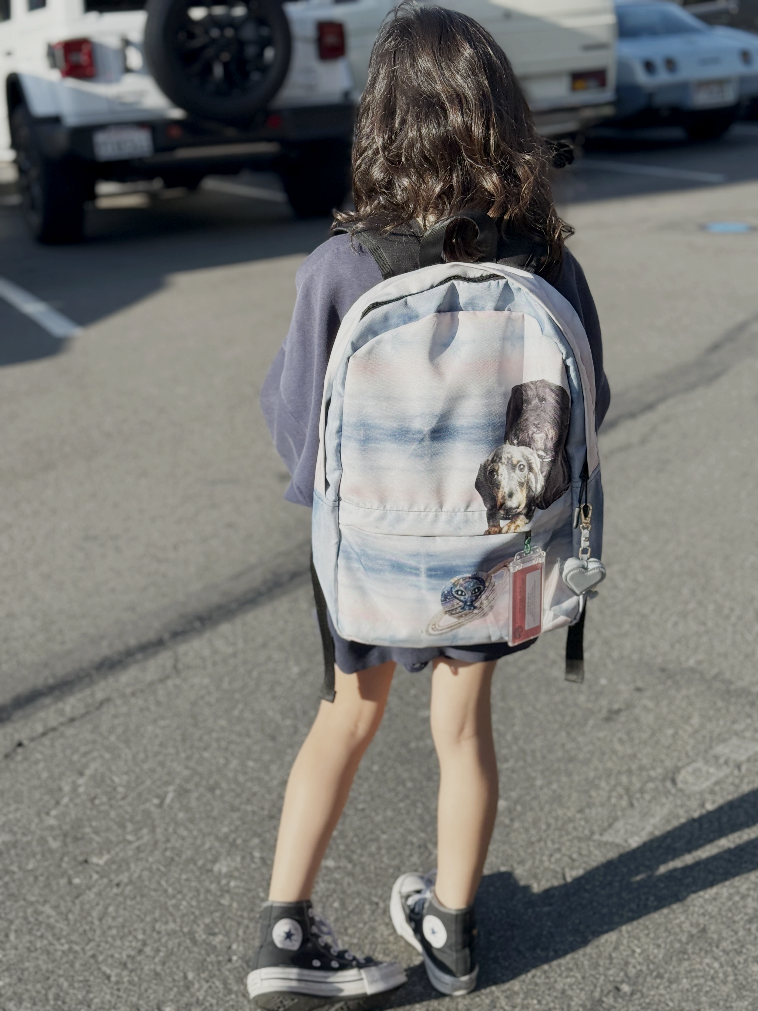 Rear view of a child walking outdoors wearing a backpack