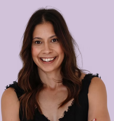 A woman with long brown hair smiling against a light purple background.