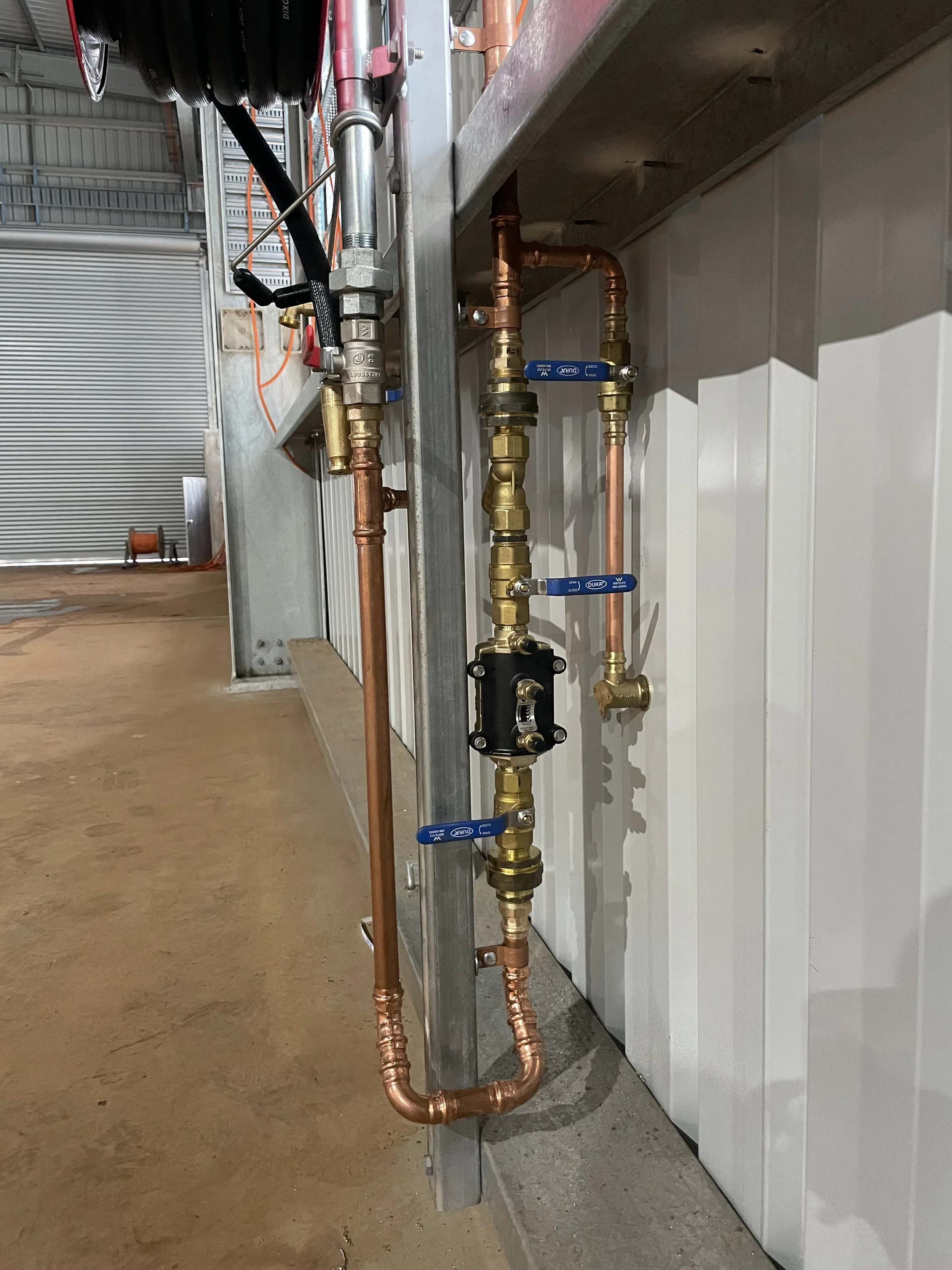 Close-up of copper and brass plumbing pipes with valves and fittings installed for fire services and backflow prevention in an industrial building under construction 