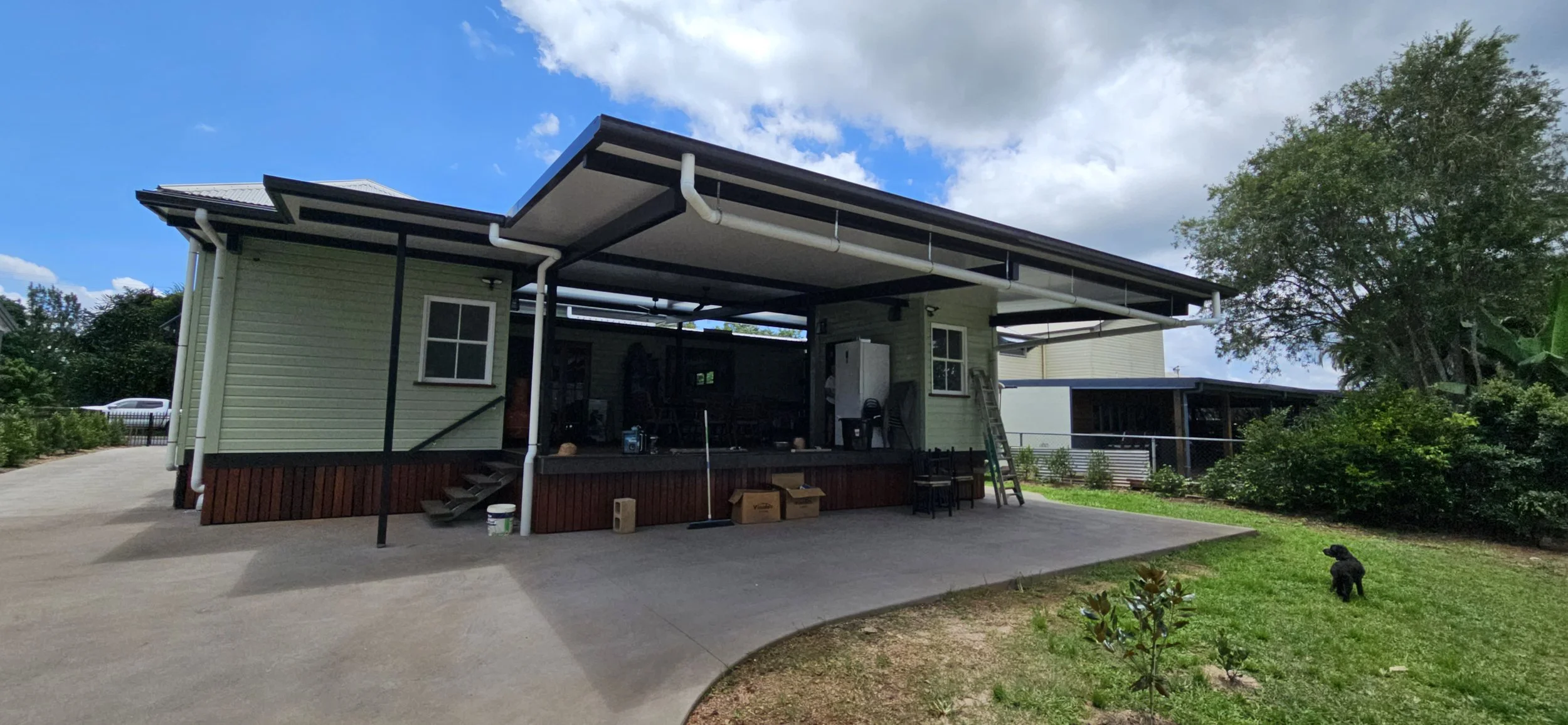 Exterior view of a renovated house with multiple new downpipes installed to divert rain water from the roof.