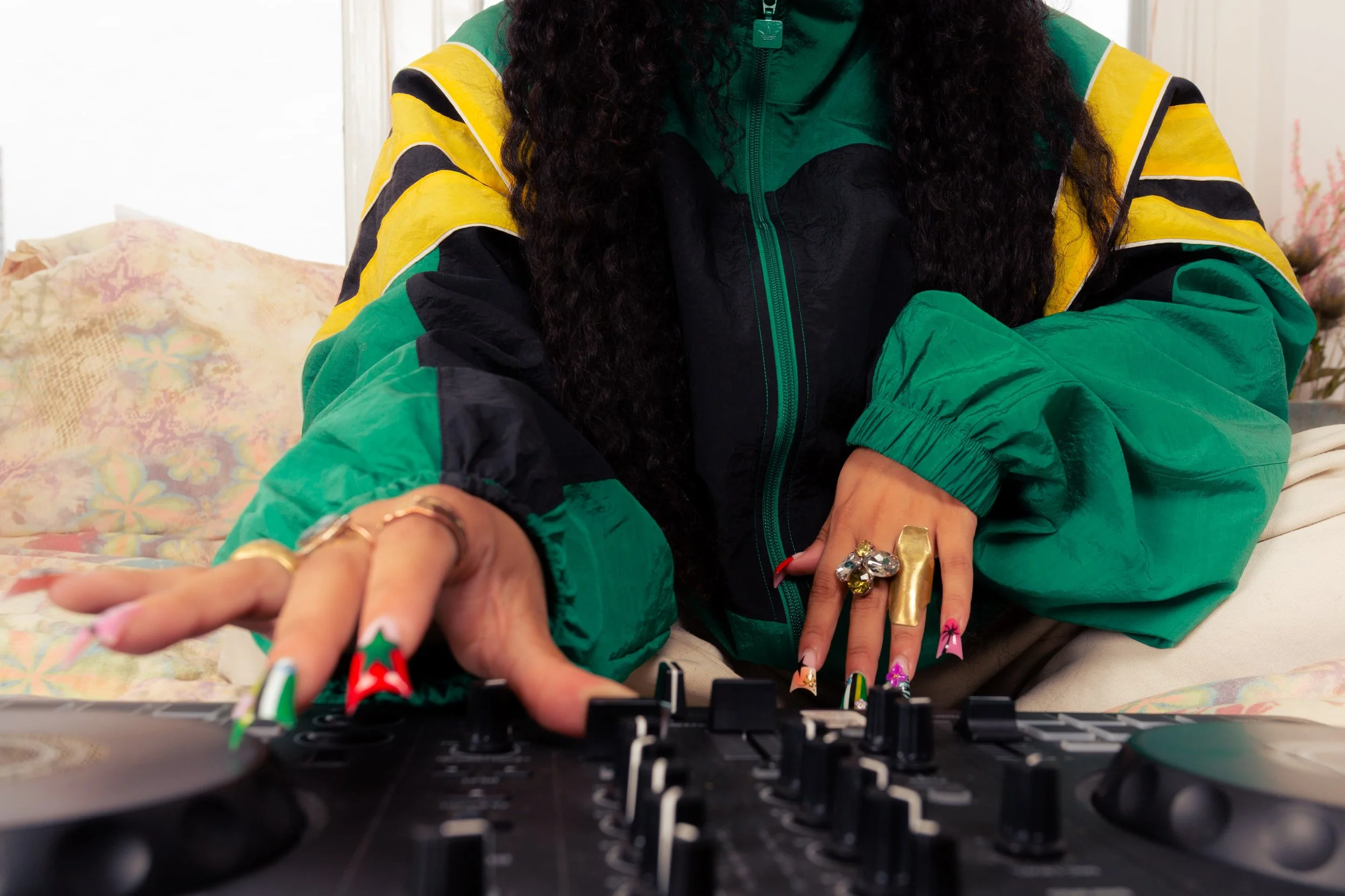 Close-up photograph of a DJ using a controller while wearing a green adidas jacket and statement jewellery, photographed by Manchester and London based photographer Yaroslav Prytula for Common Frequency.