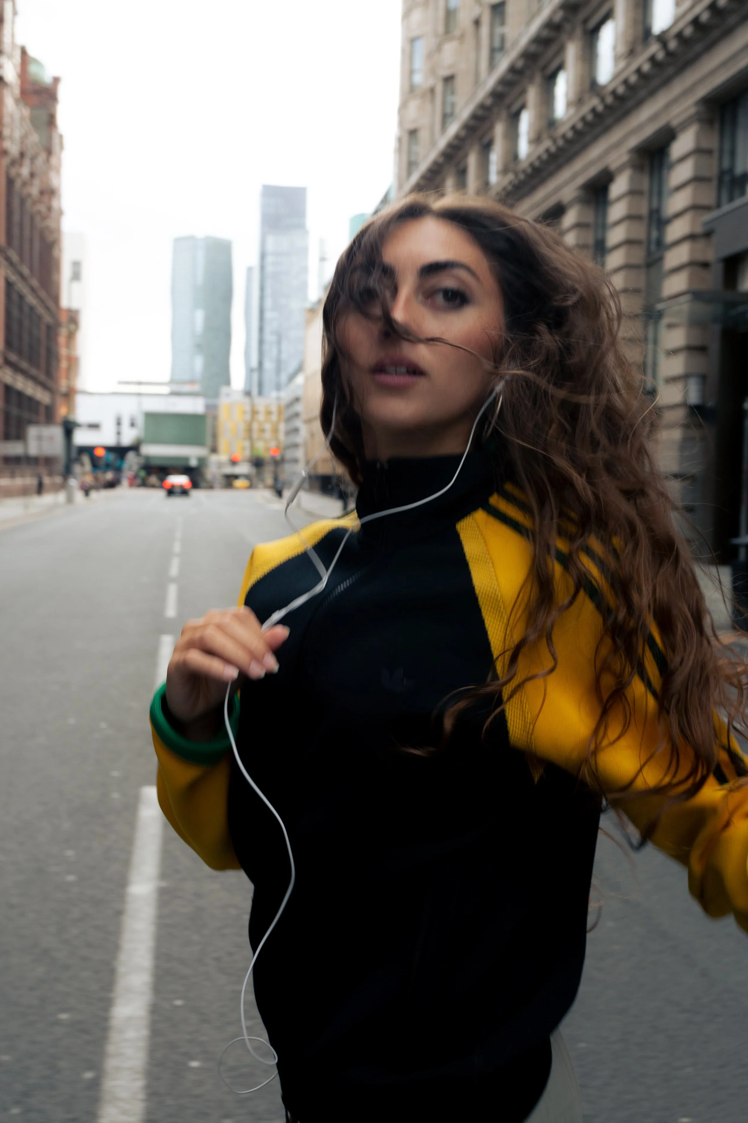 Street portrait of a woman wearing wired earphones and an adidas jacket in Manchester city centre, photographed by Manchester and London based photographer and visual artist Yaroslav Prytula for Common Frequency.