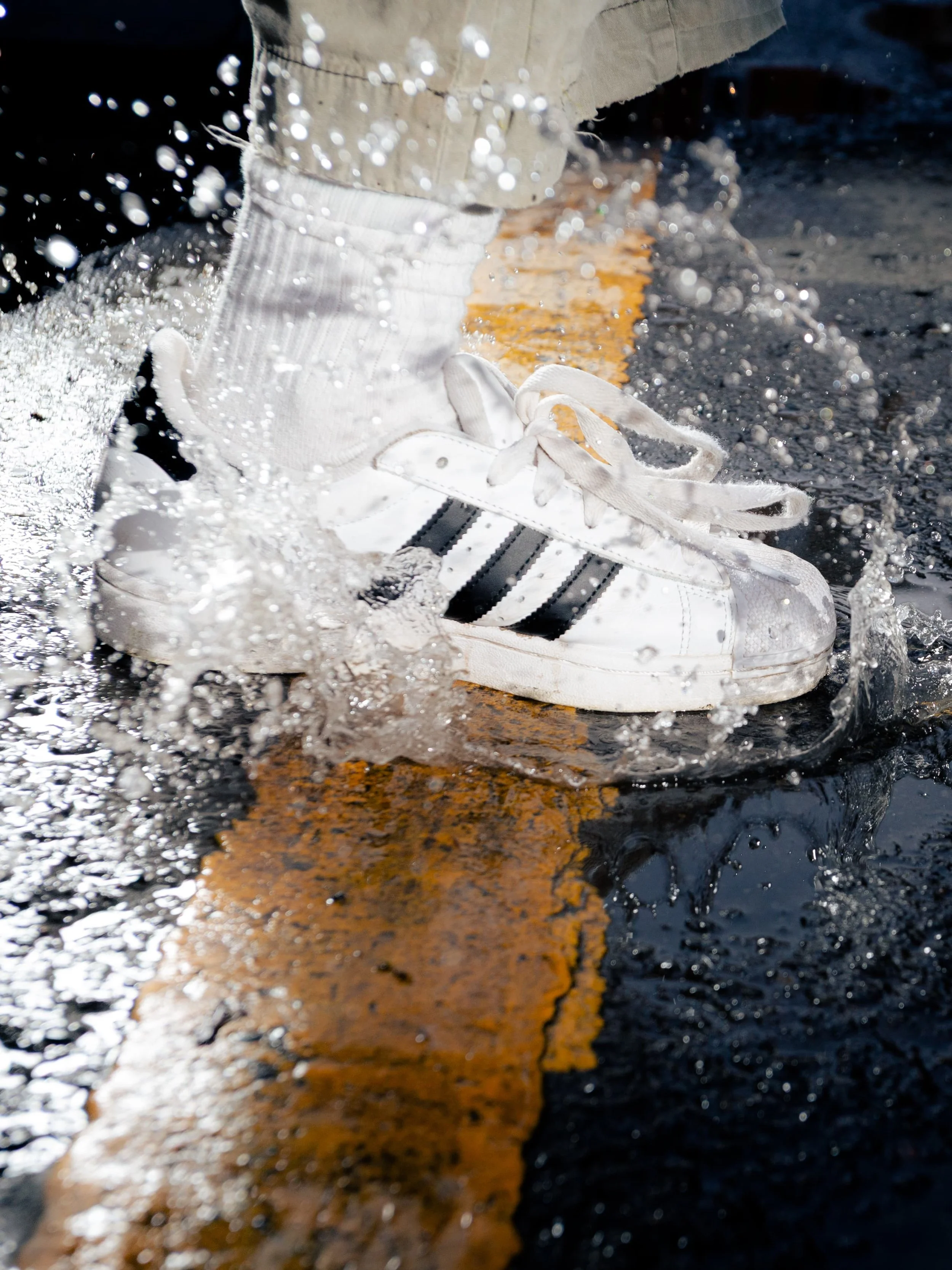 Close-up photograph of white adidas Superstar trainers stepping through water, captured by Manchester and London based photographer Yaroslav Prytula for Common Frequency.