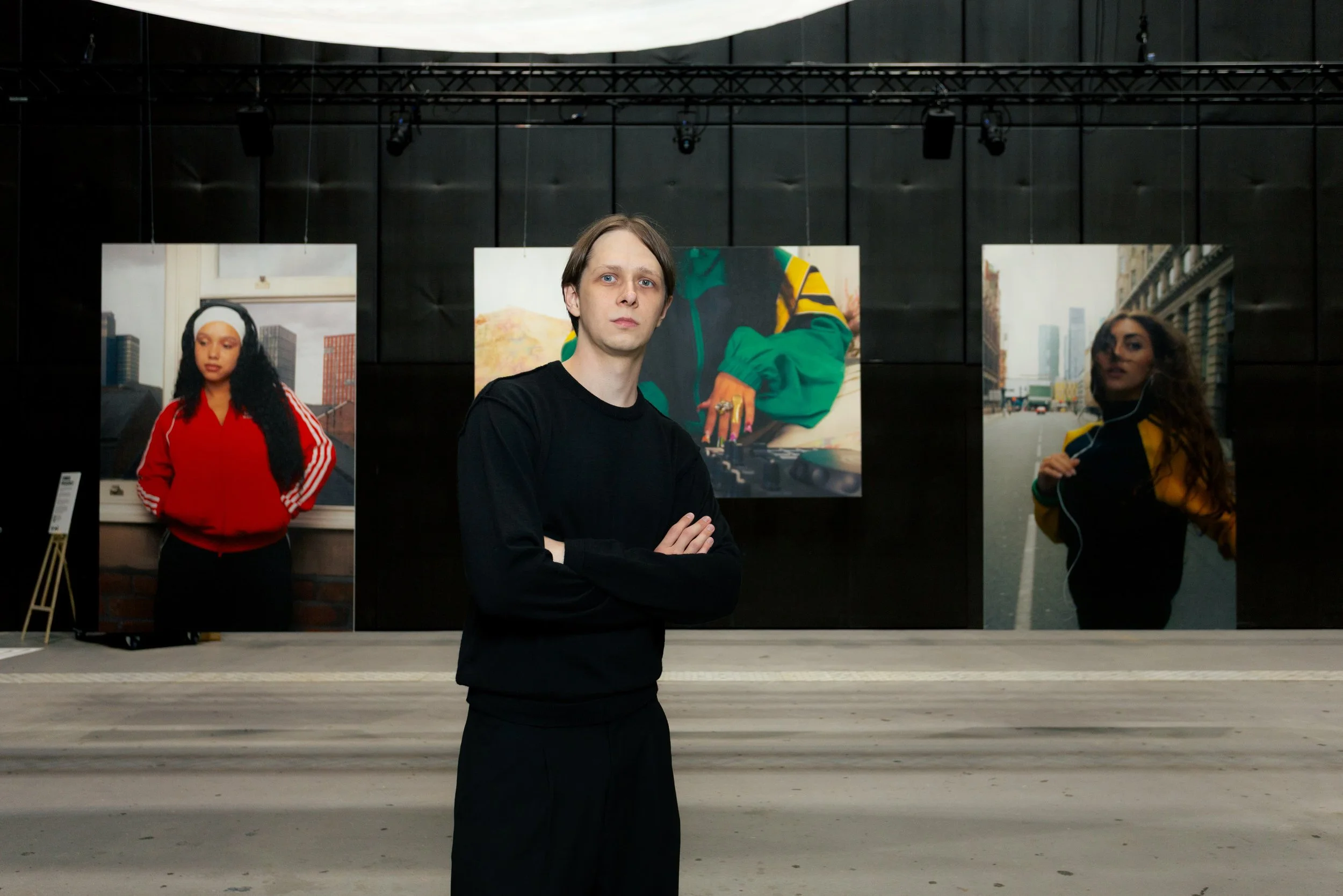 Manchester-based photographer and visual artist Yaroslav Prytula standing in front of his large-scale photographic works at the Common Frequency exhibition at Factory International.