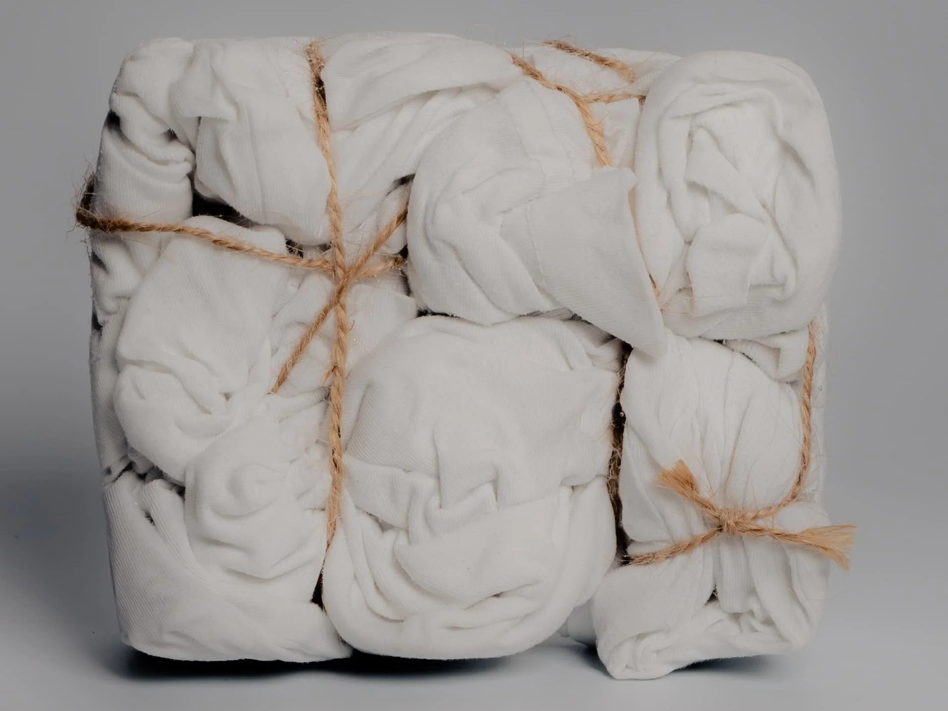 Still life photograph of bundled white fabric tied with natural twine, created by Yaroslav Prytula, still life photographer working across Manchester and London.