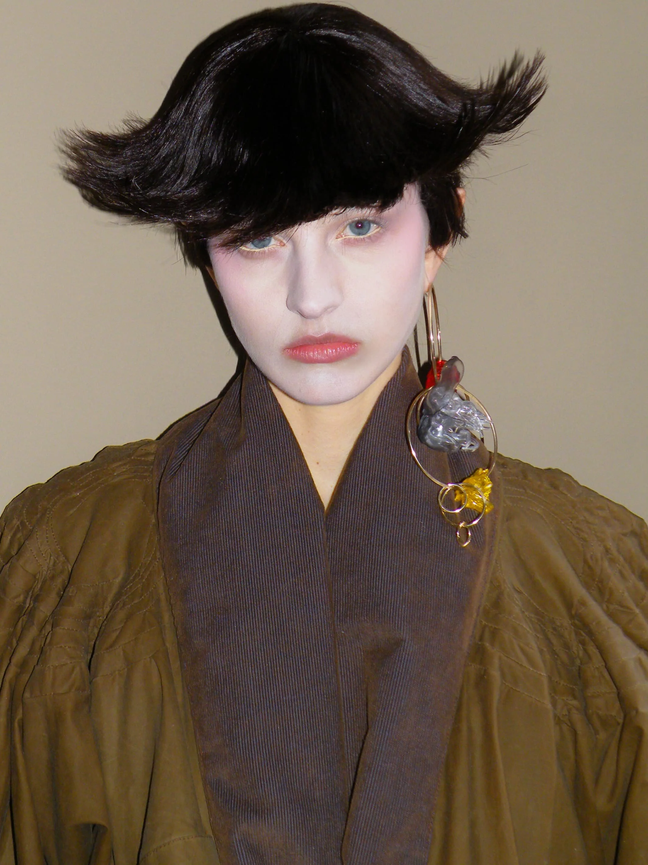 Close-up portrait of a model with sculpted black hair, blue eye makeup and statement Tétier Bijoux jewellery for Masha Popova AW26.