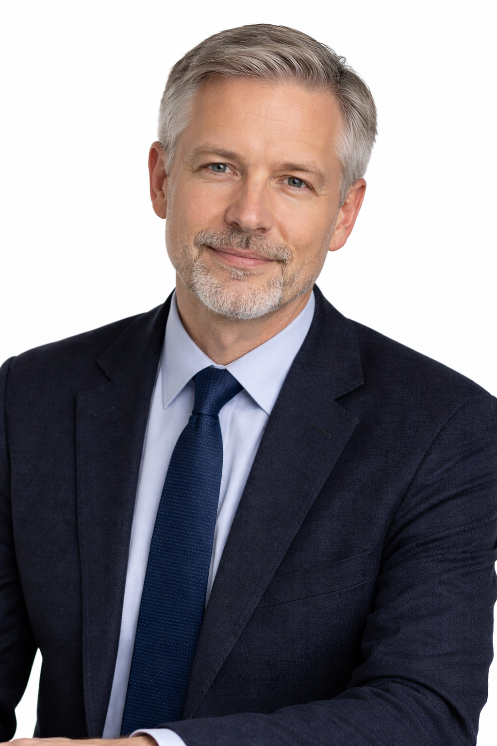 Professional middle-aged man with gray hair and beard, wearing a navy suit, light blue shirt, and dark blue tie, smiling against a white background.