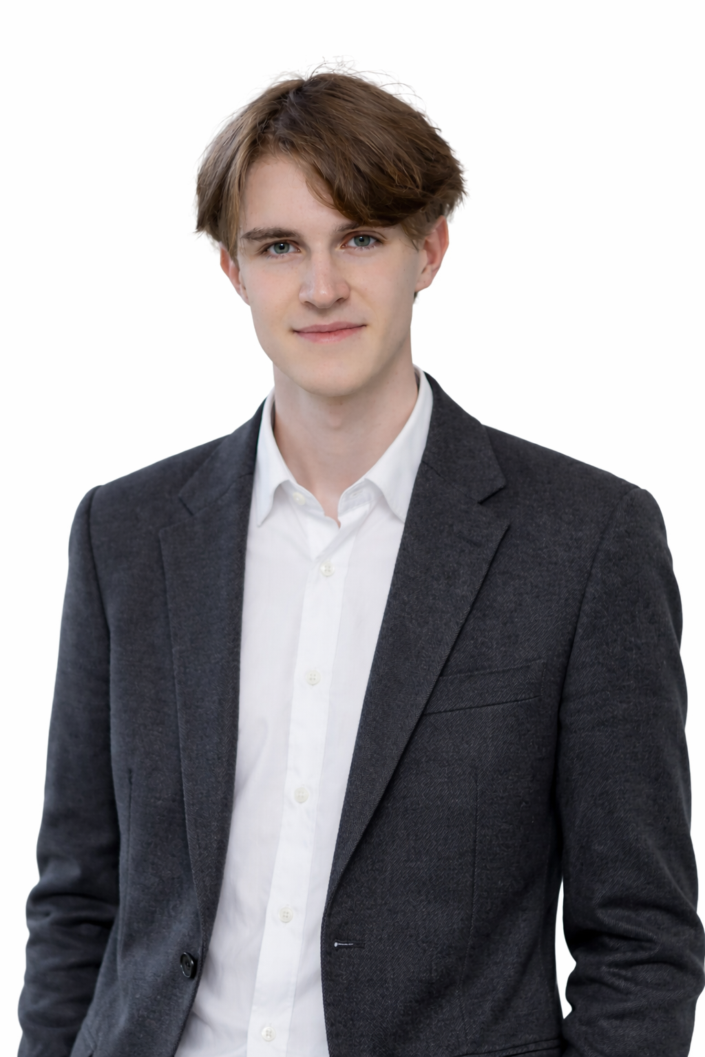 A young man with brown hair, blue eyes, wearing a white dress shirt and a dark grey blazer, standing against a plain white background.