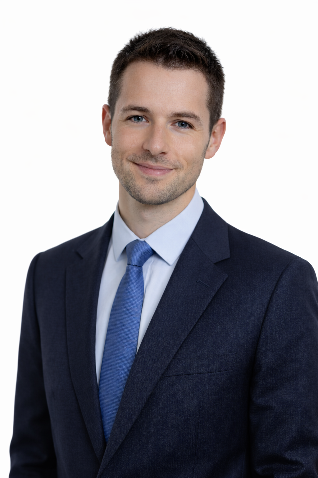 Professional headshot of a smiling man in a navy suit, light blue shirt, and matching tie, against a plain white background.