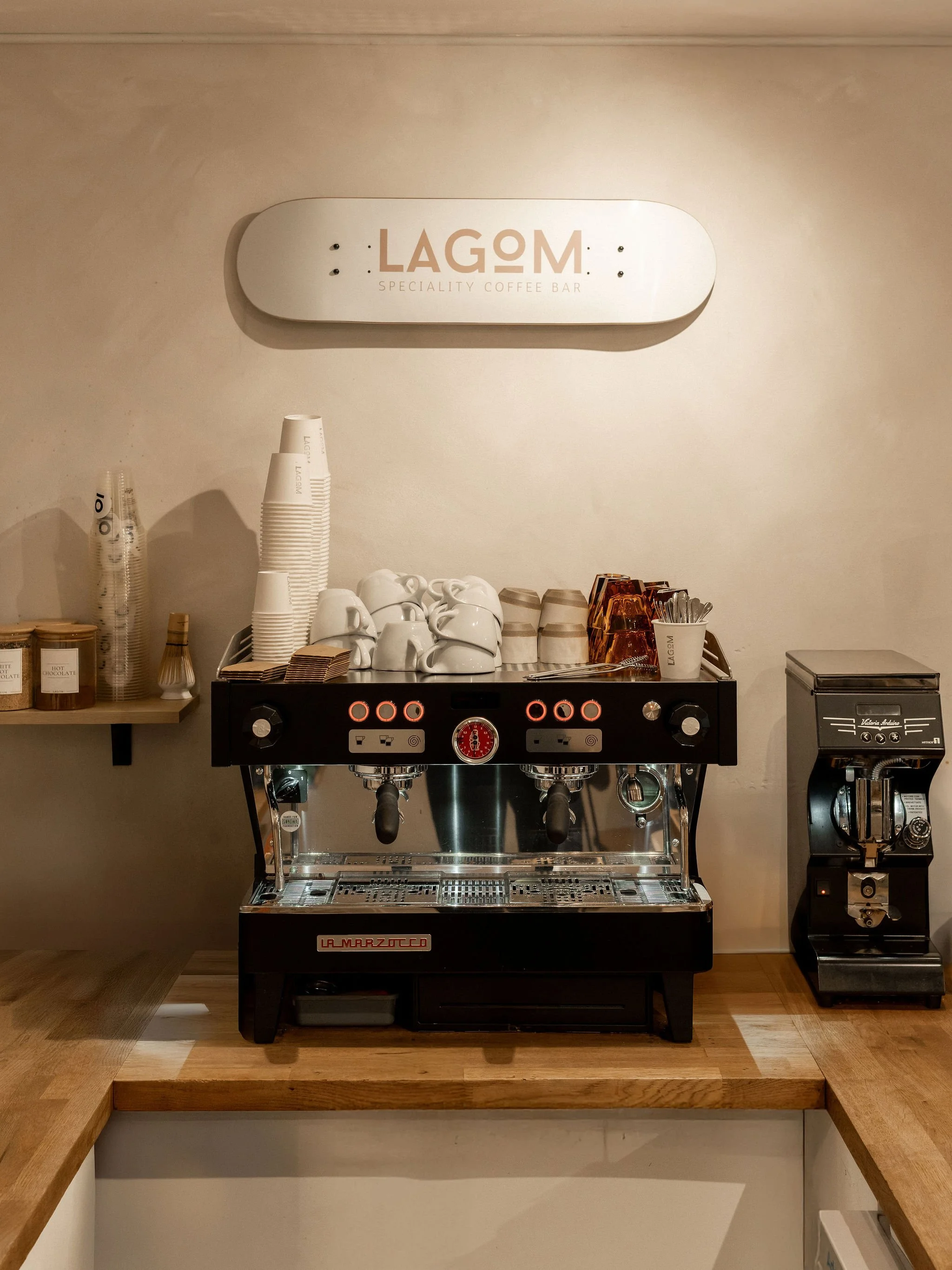 Commercial coffee machine with cups and supplies in a coffee shop named Lagom.