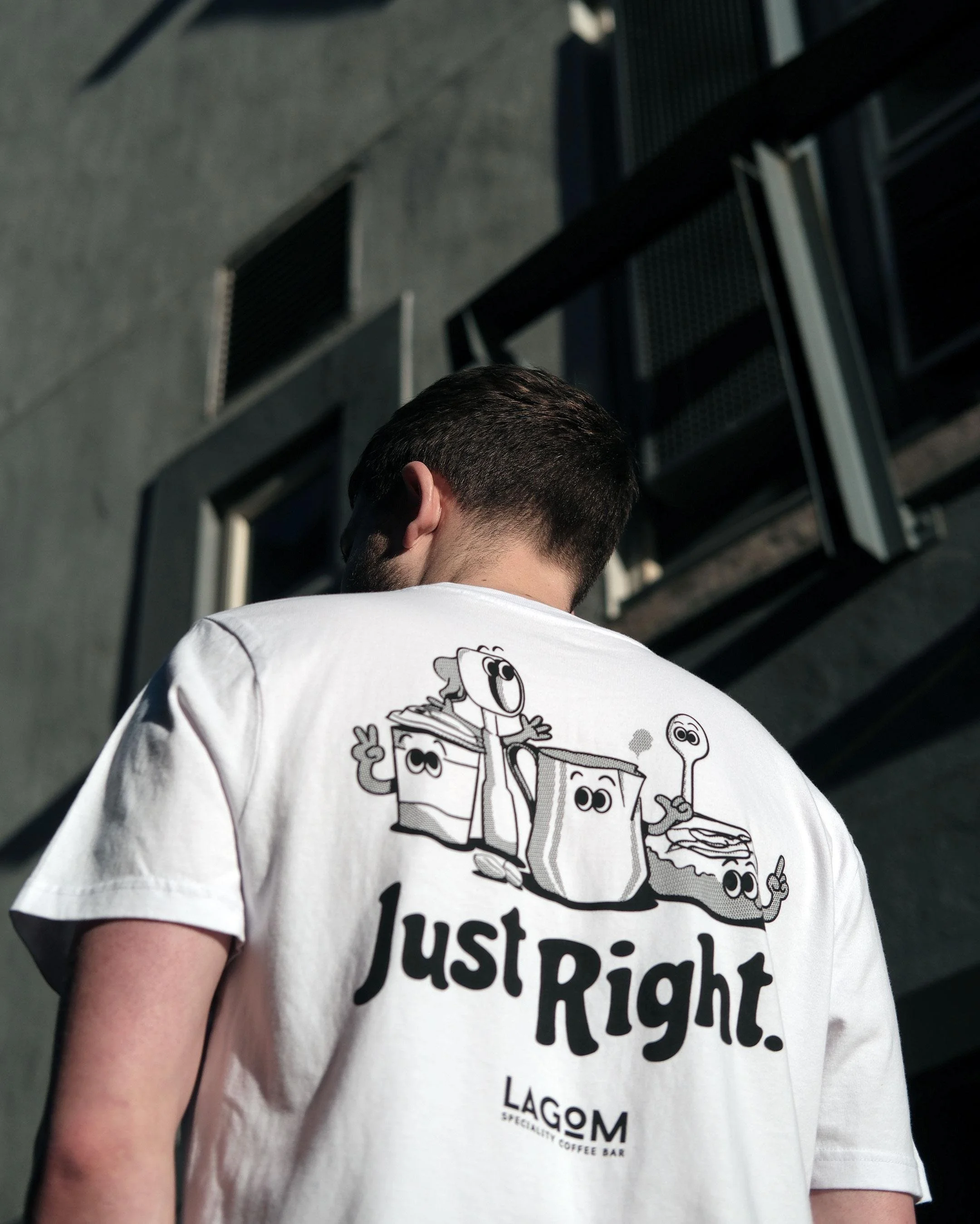 Back of a man wearing a white T-shirt with cartoon characters and the text 'Just Right'.