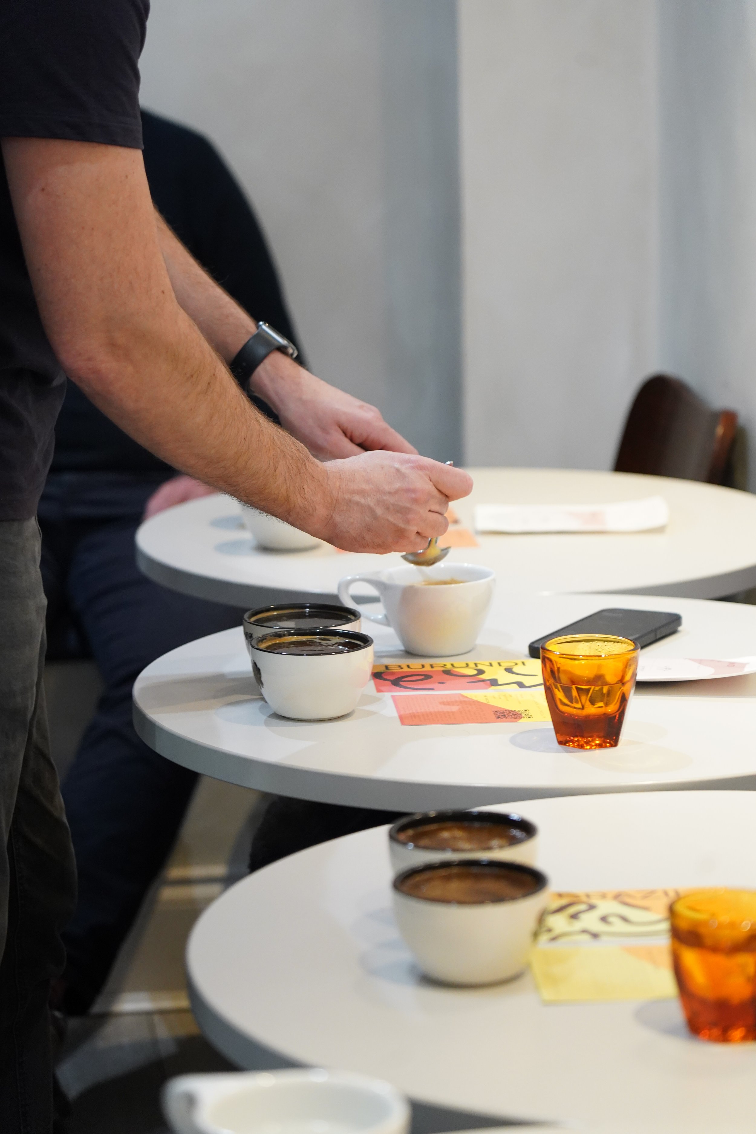 People pouring coffee or tea into cups on white tables.