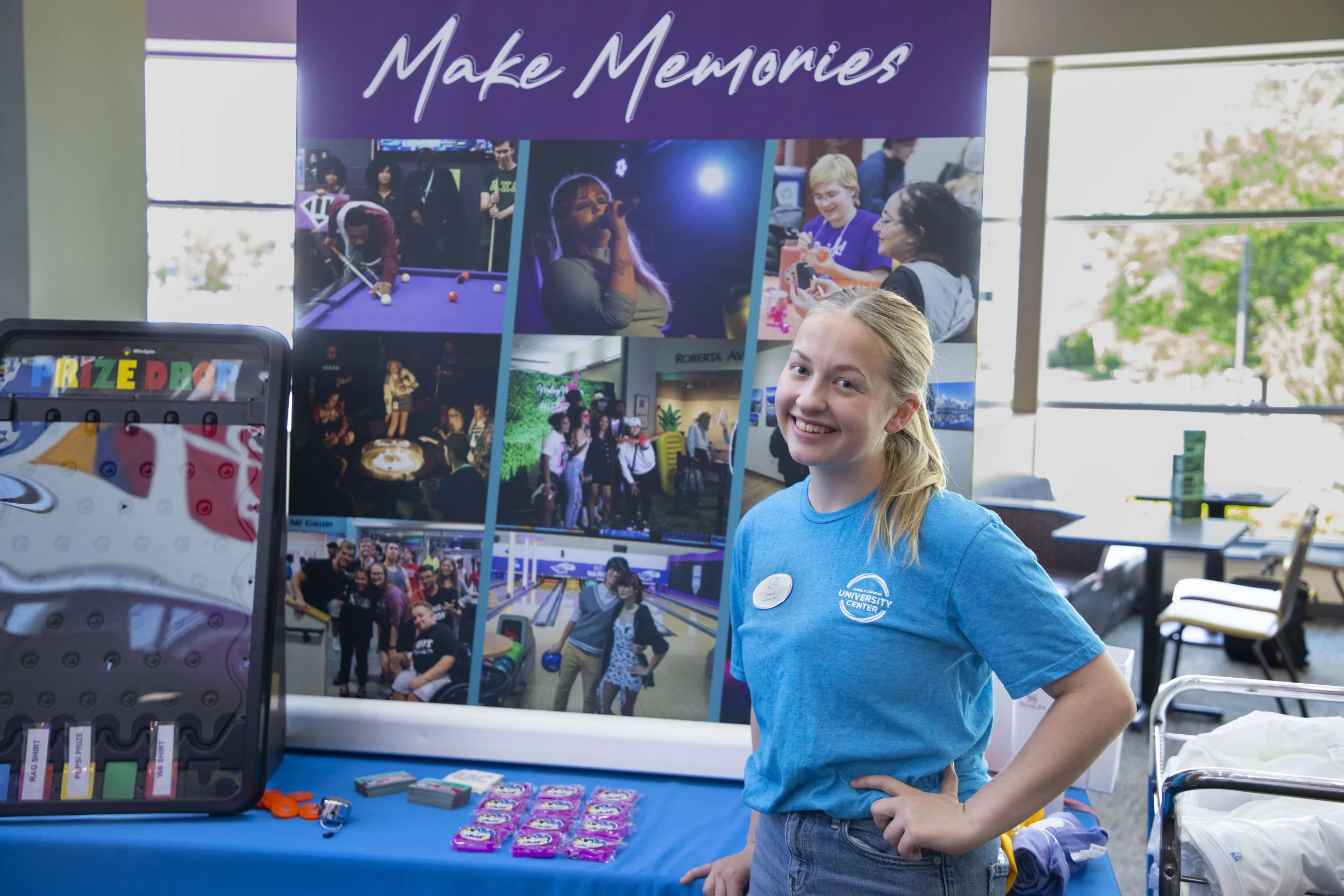 UWW Alum, Emmy Huebner, tabling during freshman orientation. Featuring a poster with a collage of past photos taken by Mangan in the UC.