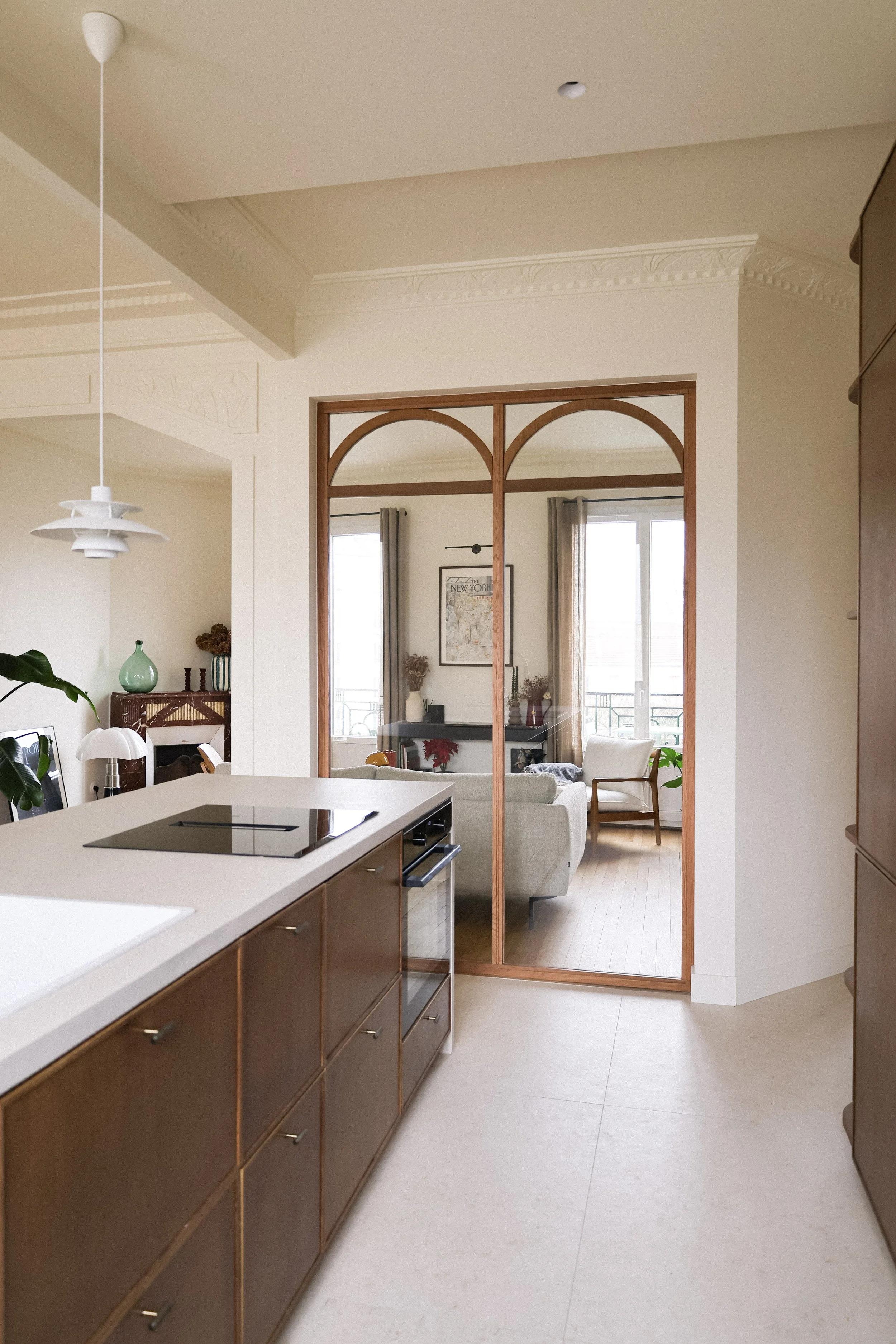 Vue de la cuisine ouverte conduisant à un salon avec canapé et grande fenêtre.