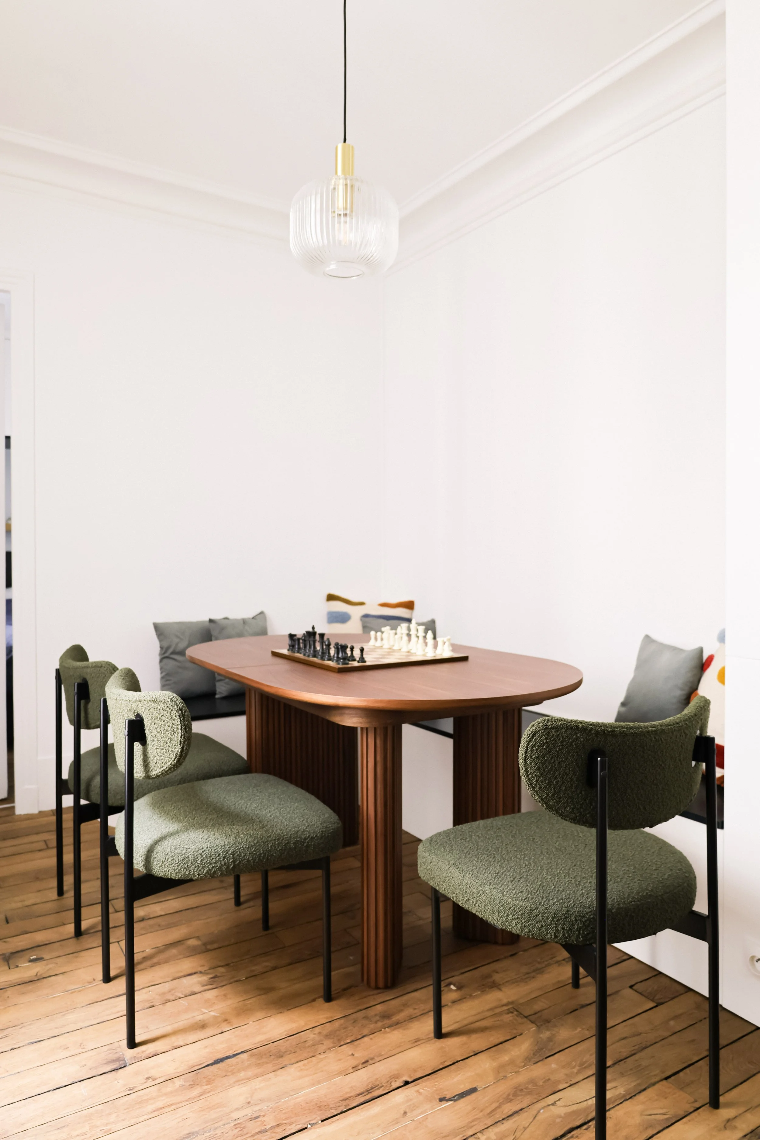 Architecture d’intérieur contemporaine minimaliste france : design sur mesure, décoration haut de gamme, gestion de chantier, conception. Salle à manger moderne avec une table en bois ovale, six chaises vertes et un éclairage suspendu.