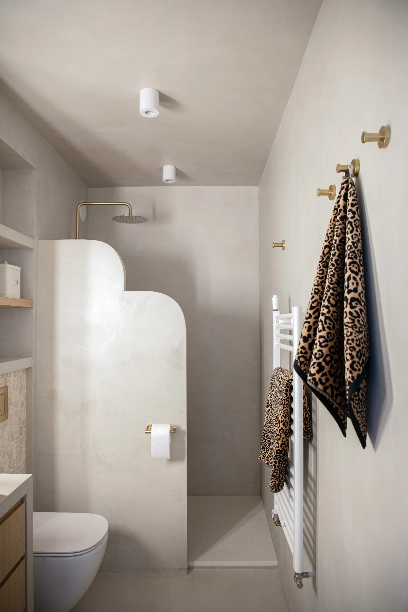 Architecture d’intérieur contemporaine minimaliste france : design sur mesure, décoration haut de gamme, gestion de chantier, conception. Salle de bain minimaliste avec toilettes modernes, douche séparée, serviettes zébrées, murs clairs