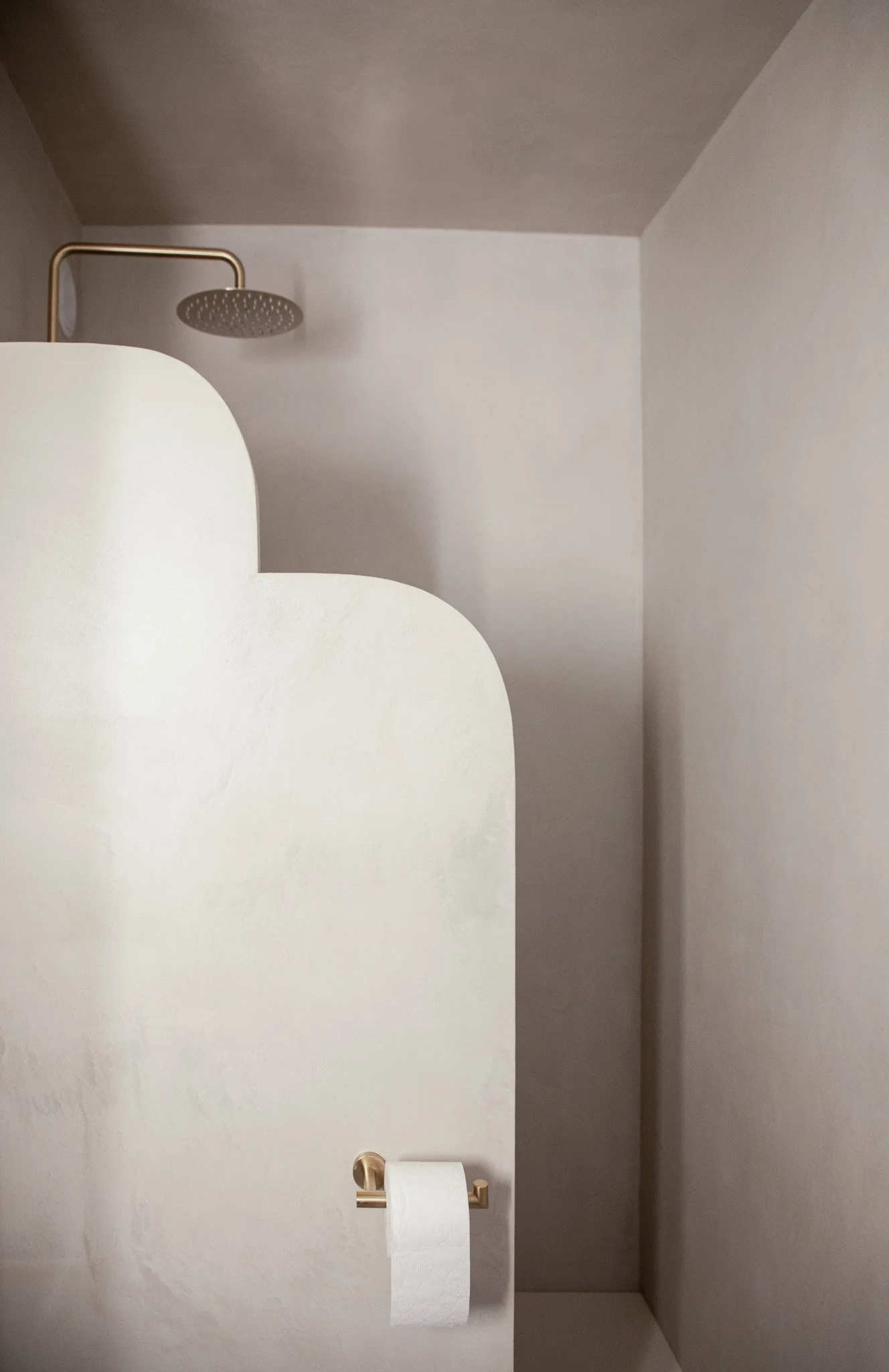 Architecture d’intérieur contemporaine minimaliste france : design sur mesure, décoration haut de gamme, gestion de chantier, conception. Cabine de toilette avec mur en forme de vagues et pommeau de douche en arrière-plan.