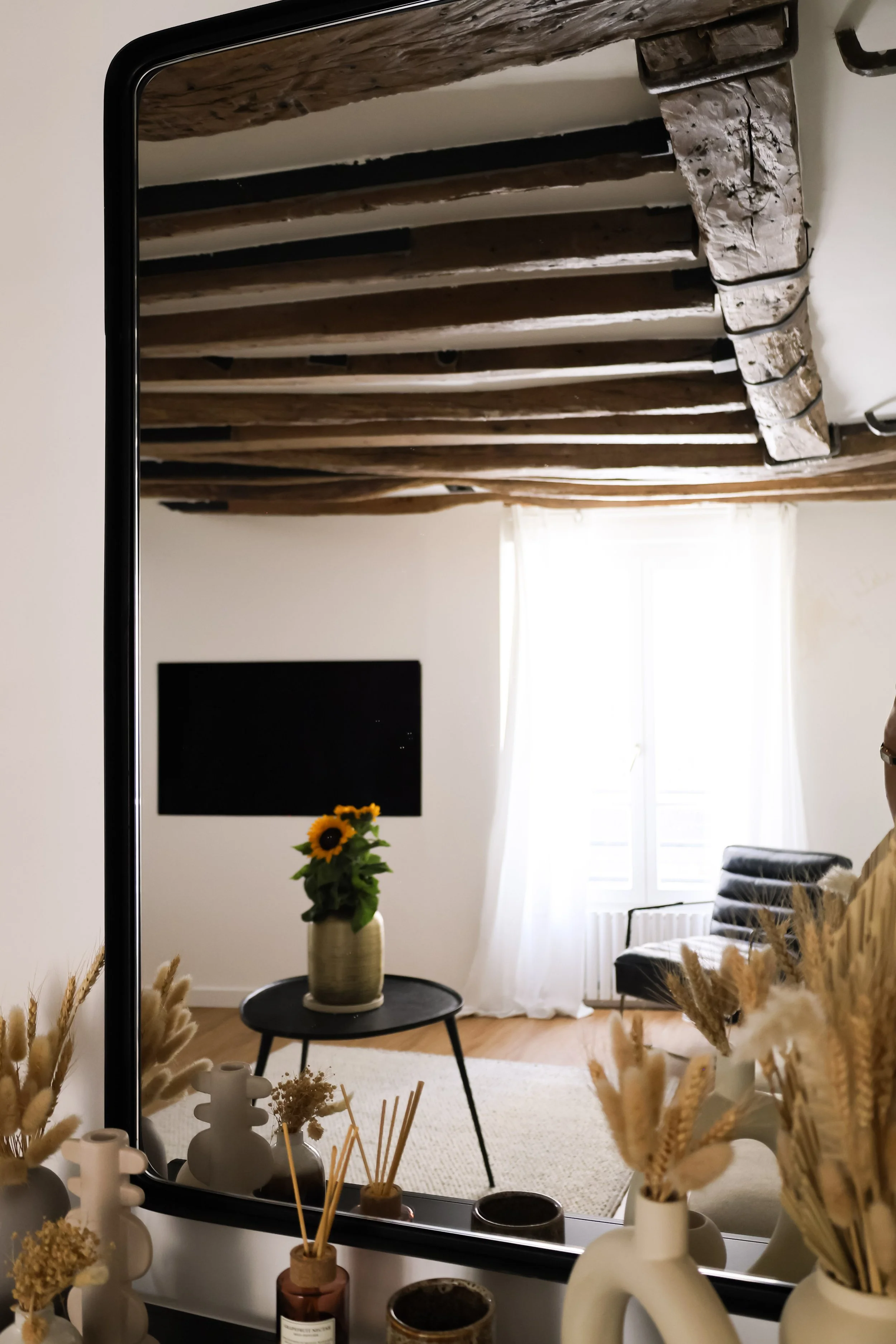 Architecture d’intérieur contemporaine minimaliste france : design sur mesure, décoration haut de gamme, gestion de chantier, conception. Reflet d’un salon avec un mur blanc, des rideaux blancs, une plante aux tournesols dans un pot beige