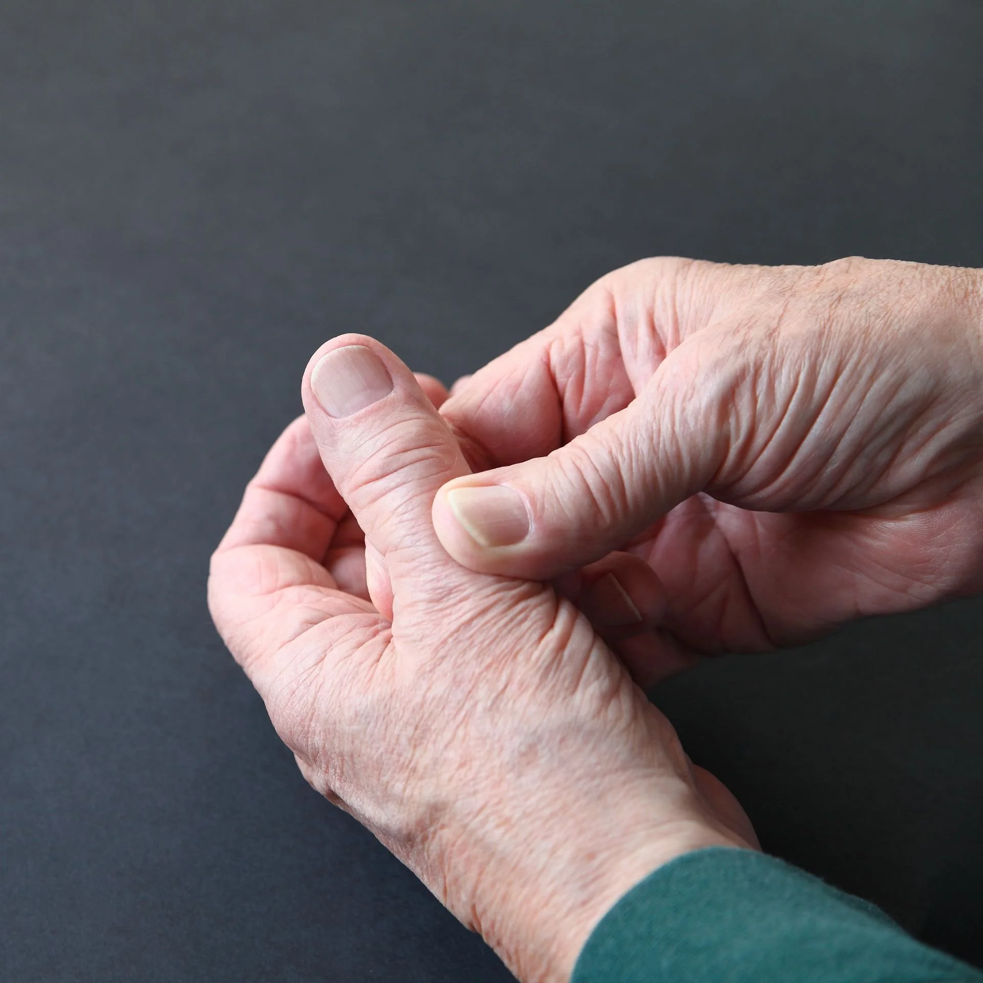 Homme âgé se tenant le pouce à cause d'une douleur qui nécessite la pose d'une prothèse