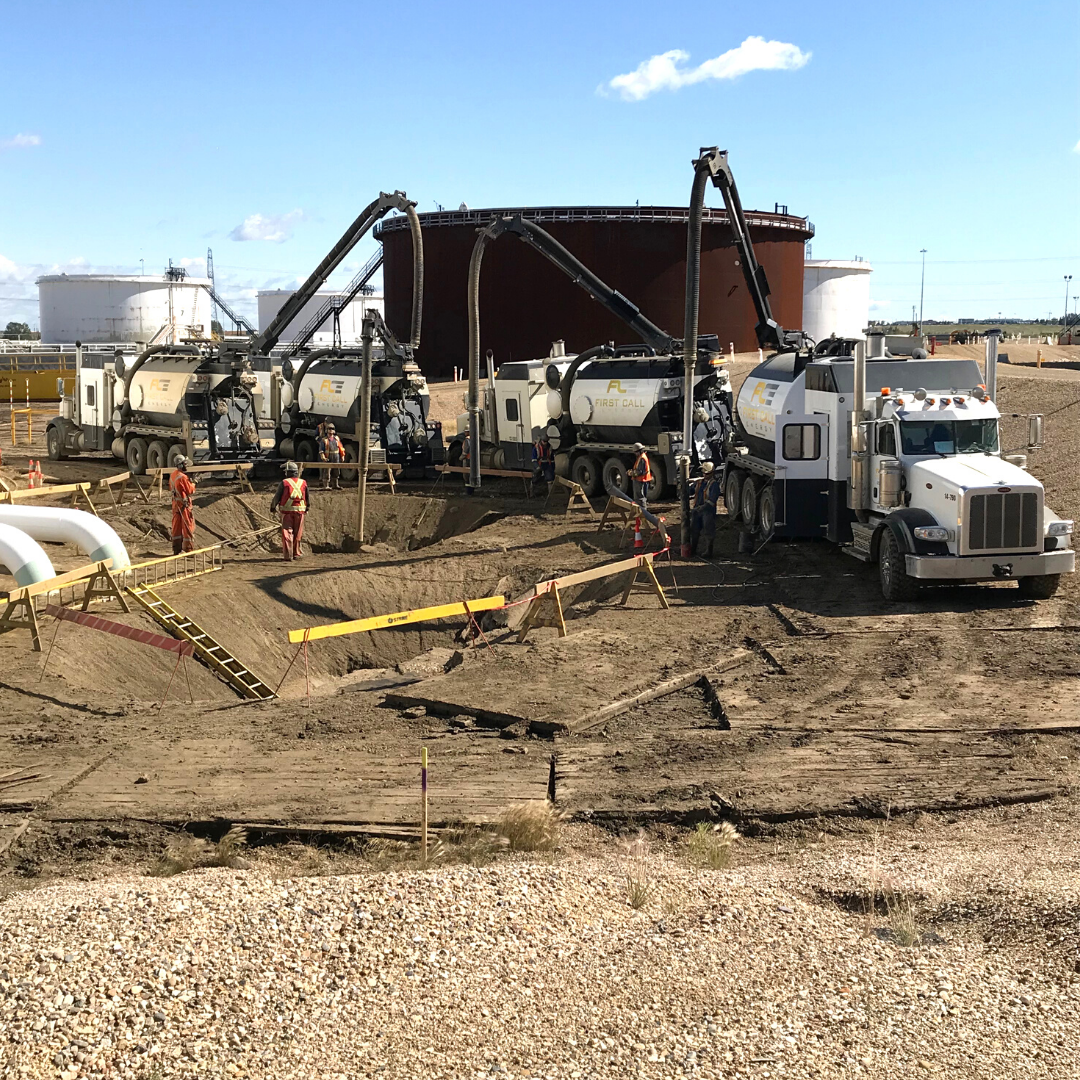Construction site with trucks and workers alongside large storage tanks