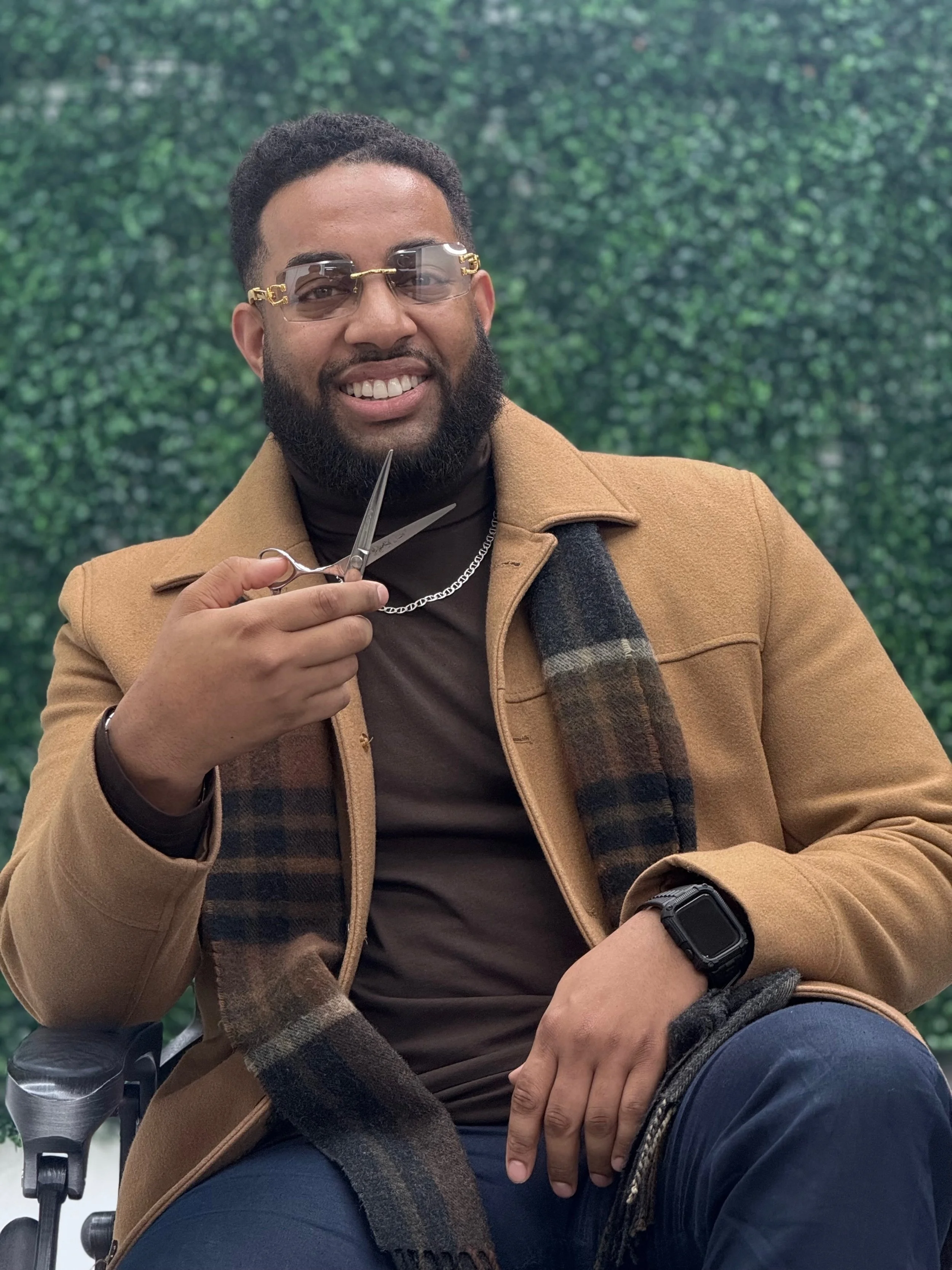 Man sitting on outdoor steps wearing a black t-shirt, black pants, and white sneakers.