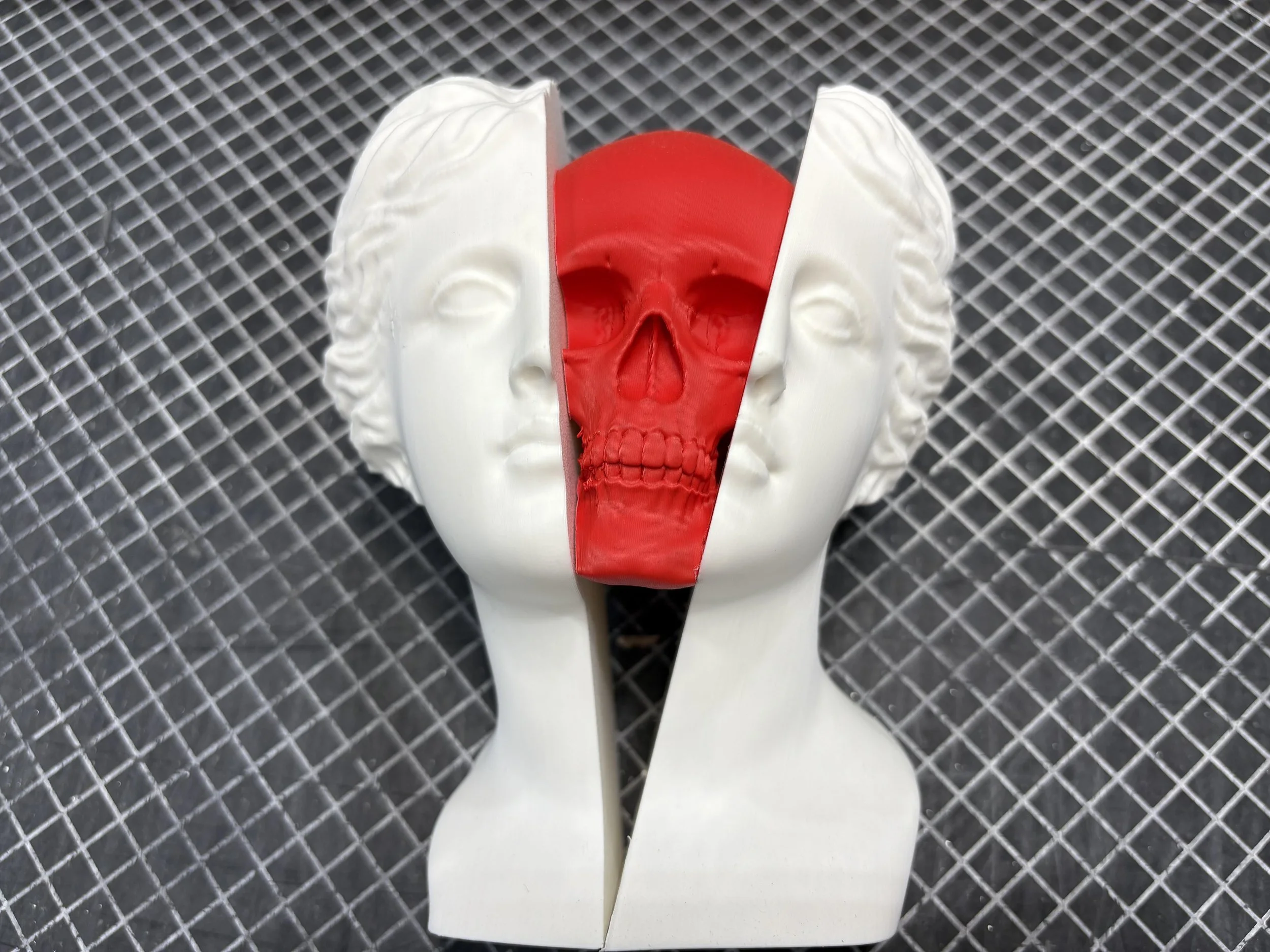 White classical bust split with a red skull inside on grid background.