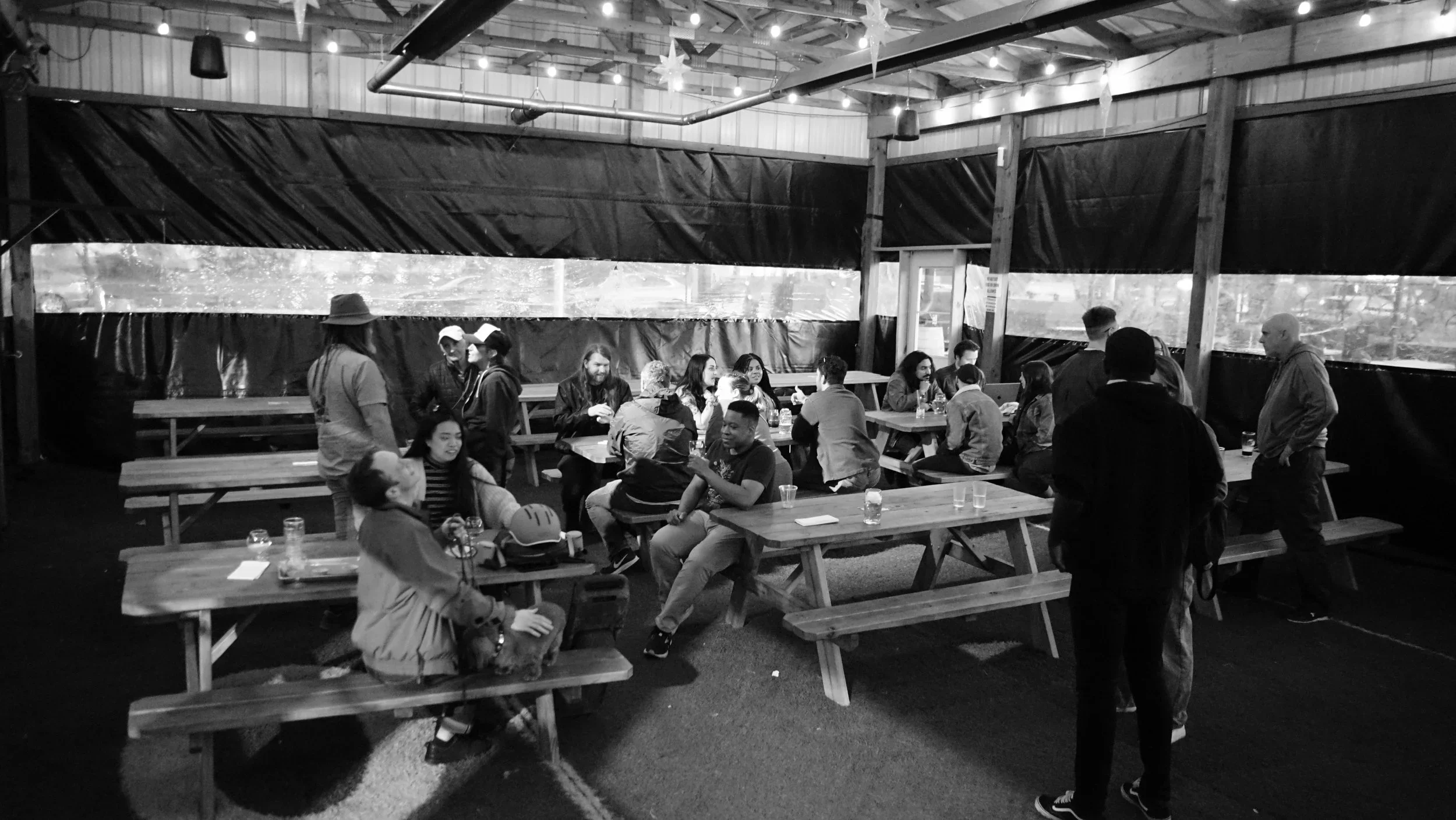 A diverse group of Detroit community members gathered and connecting at a Crux Social event under warm string lights