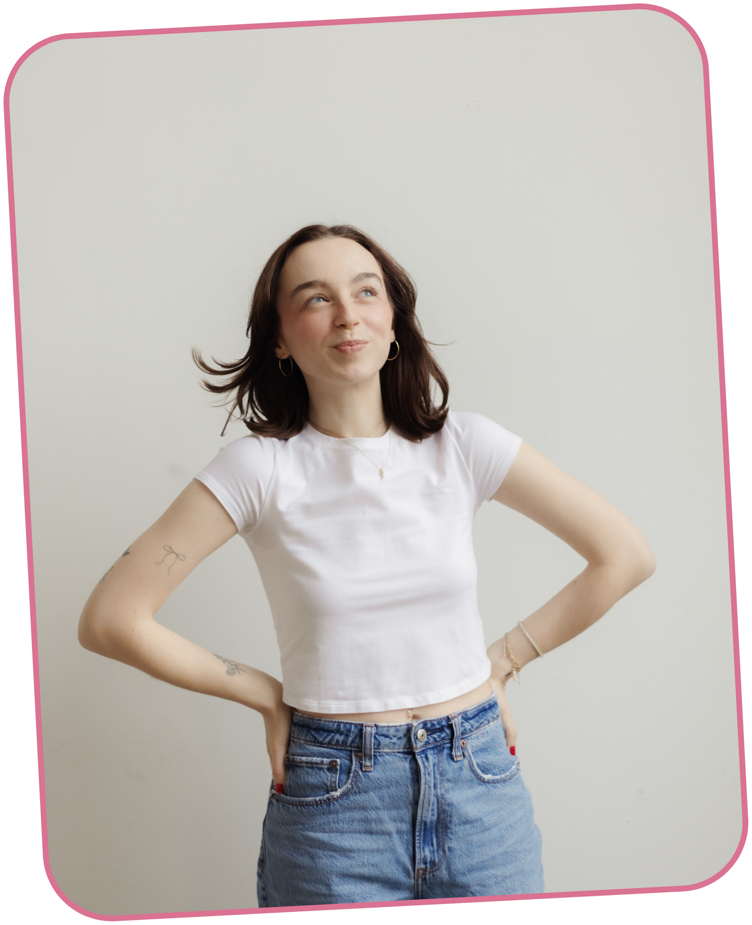 Girl wearing blue jeans and a white t-shirt standing with hands on her hips and smiling at the camera.