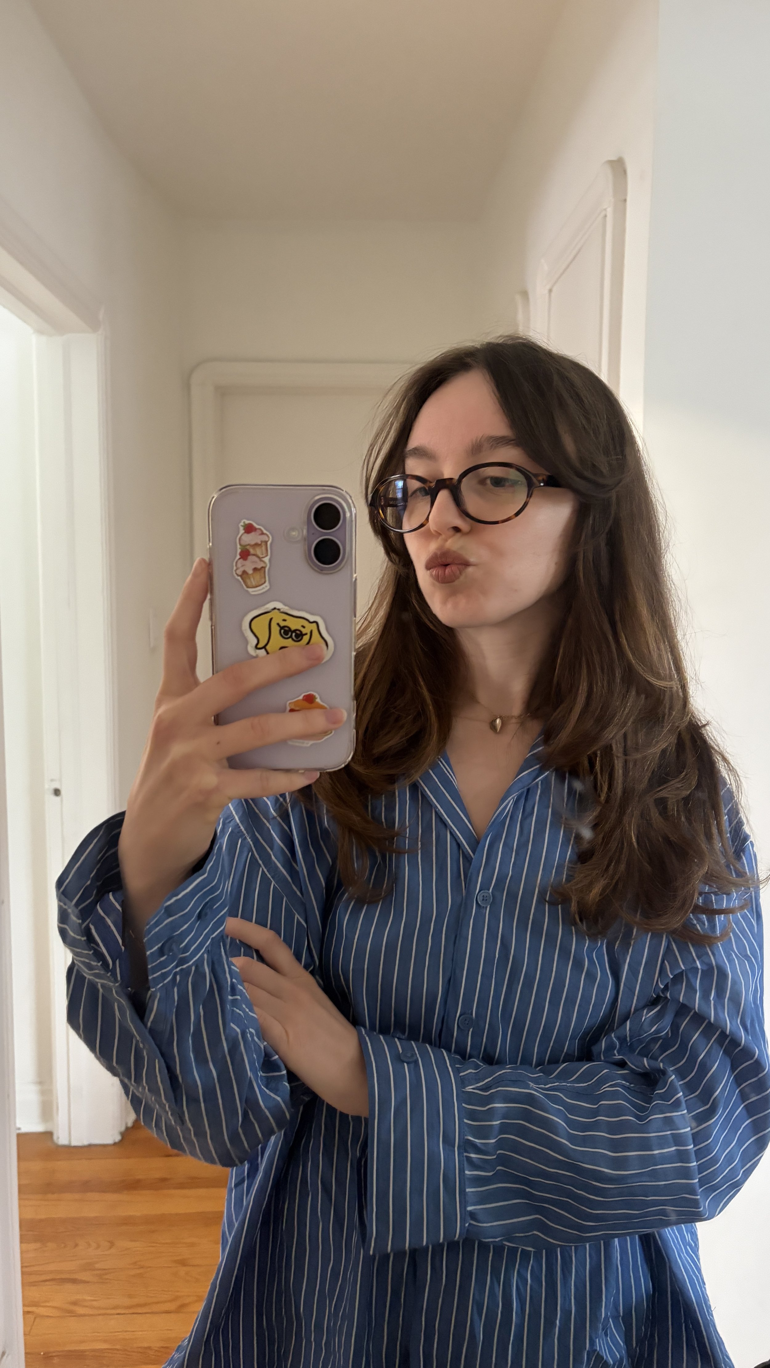 Girl wearing a blue button-down with stripes taking a selfie in front of a mirror