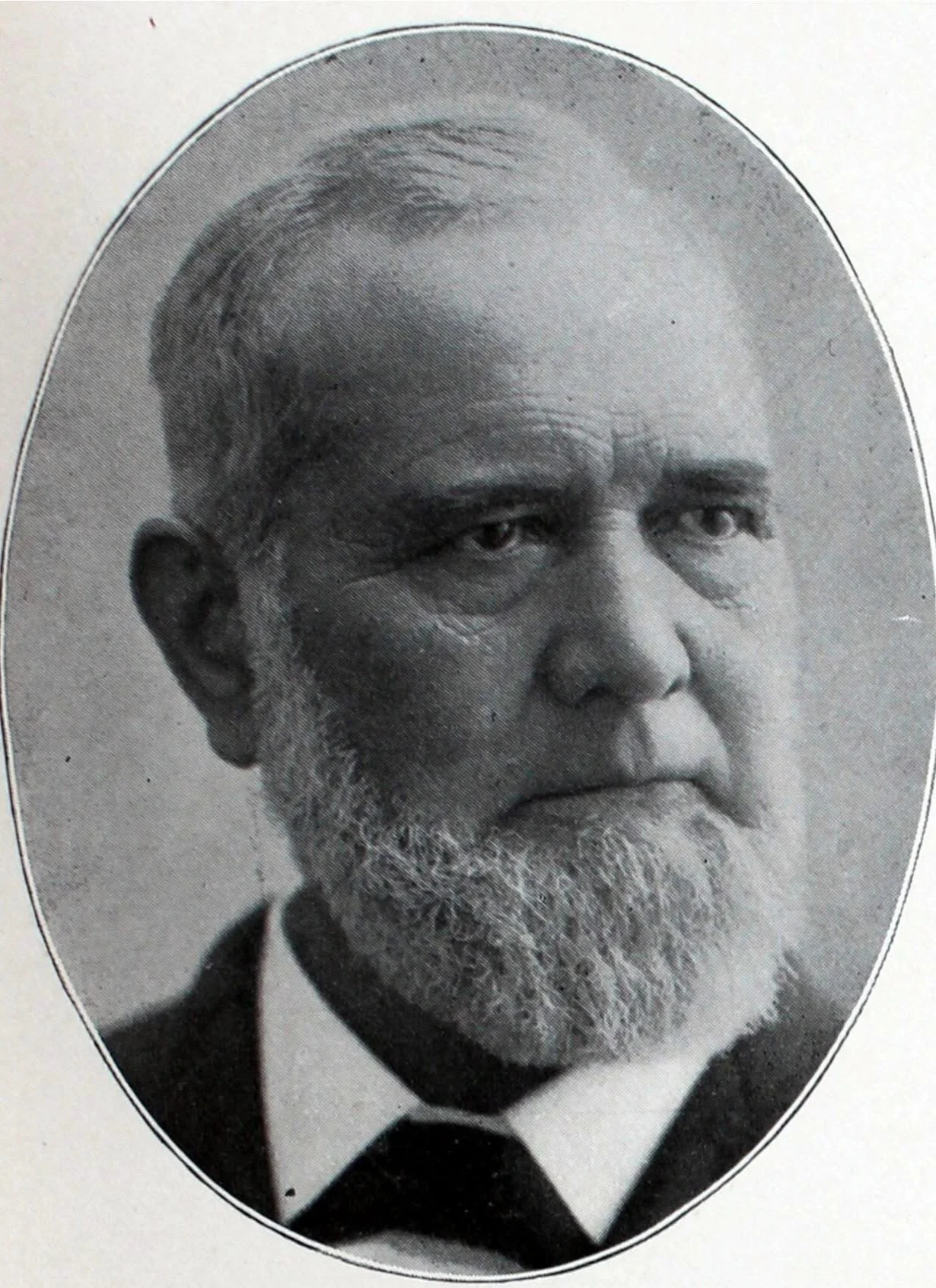 Black and white portrait photo of an older man with a full beard, mustache, and short hair, dressed in formal attire.