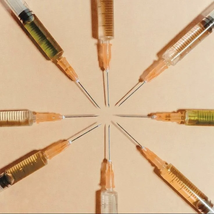 Eight syringes arranged in a circular pattern with their tips pointing inward.