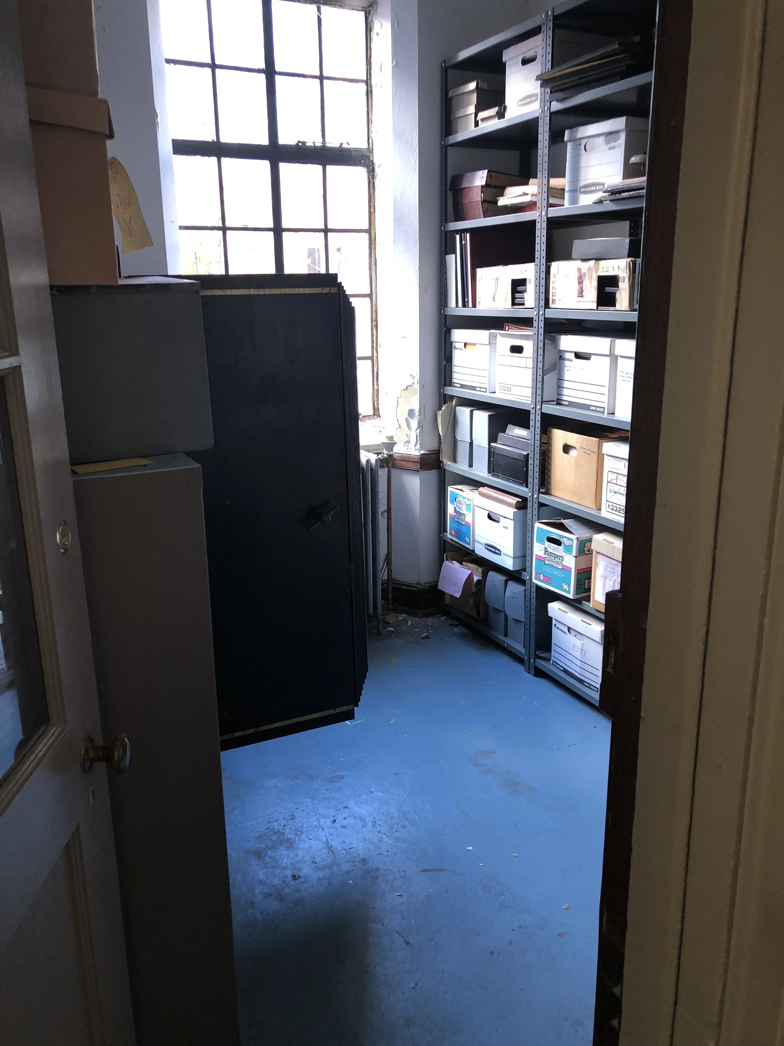 St. Luke's archive room. Two shelving units of archive boxes and a window.