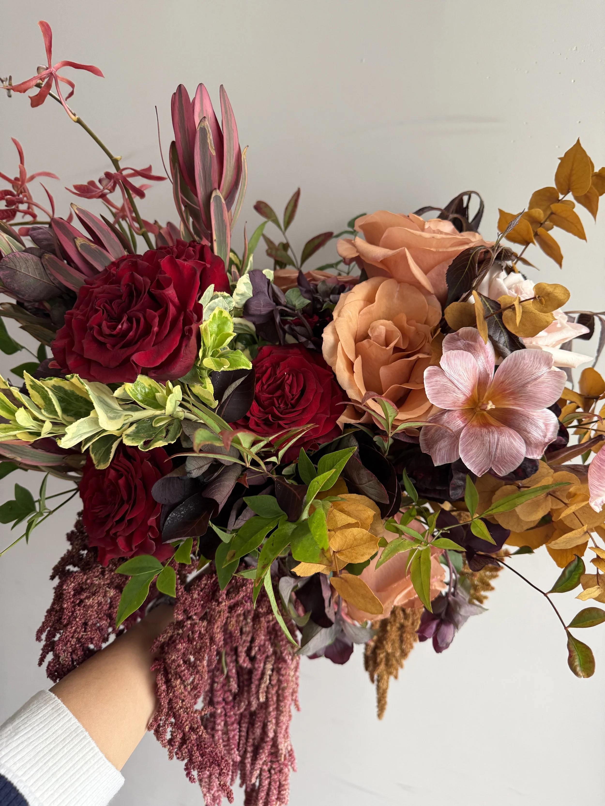 Colorful wedding bouquet with mixed flowers and greenery held by hand