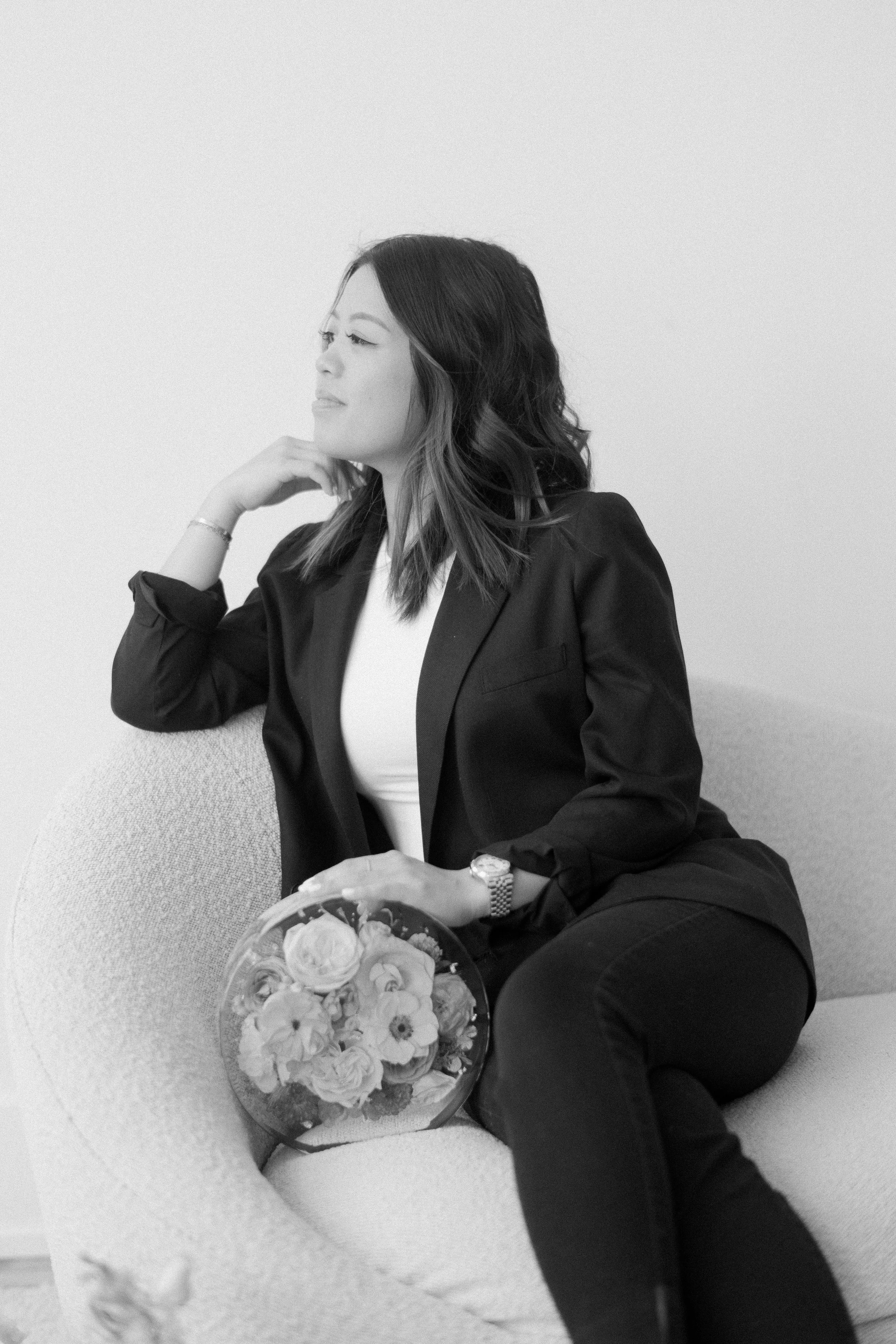 Vivian, owner of VIVIAN x CO, seated with a flower bouquet preserved in resin in her Chicago floral preservation studio