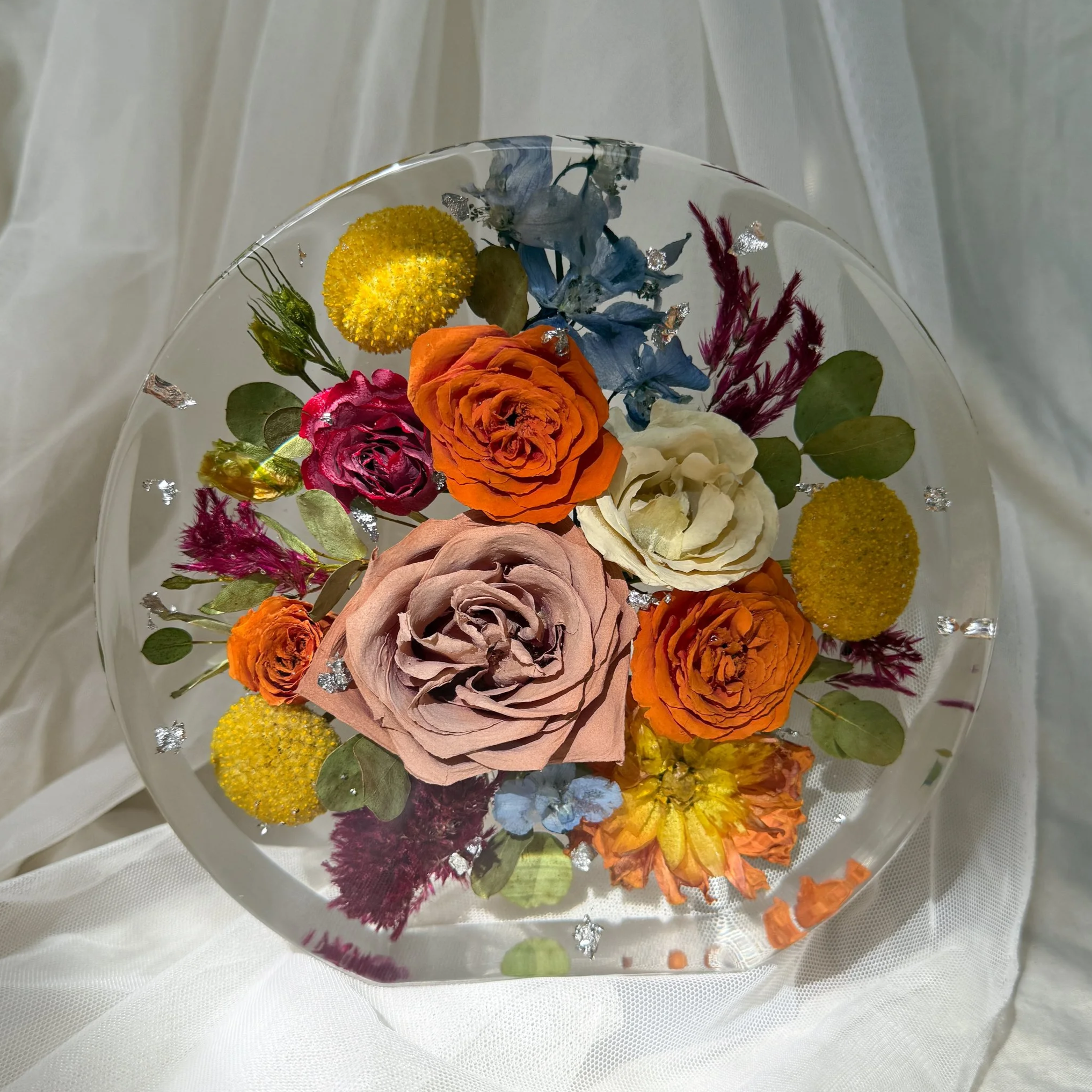 7-inch standing resin circle featuring preserved orange and mauve roses, blue hydrangea, yellow billy buttons, and greenery