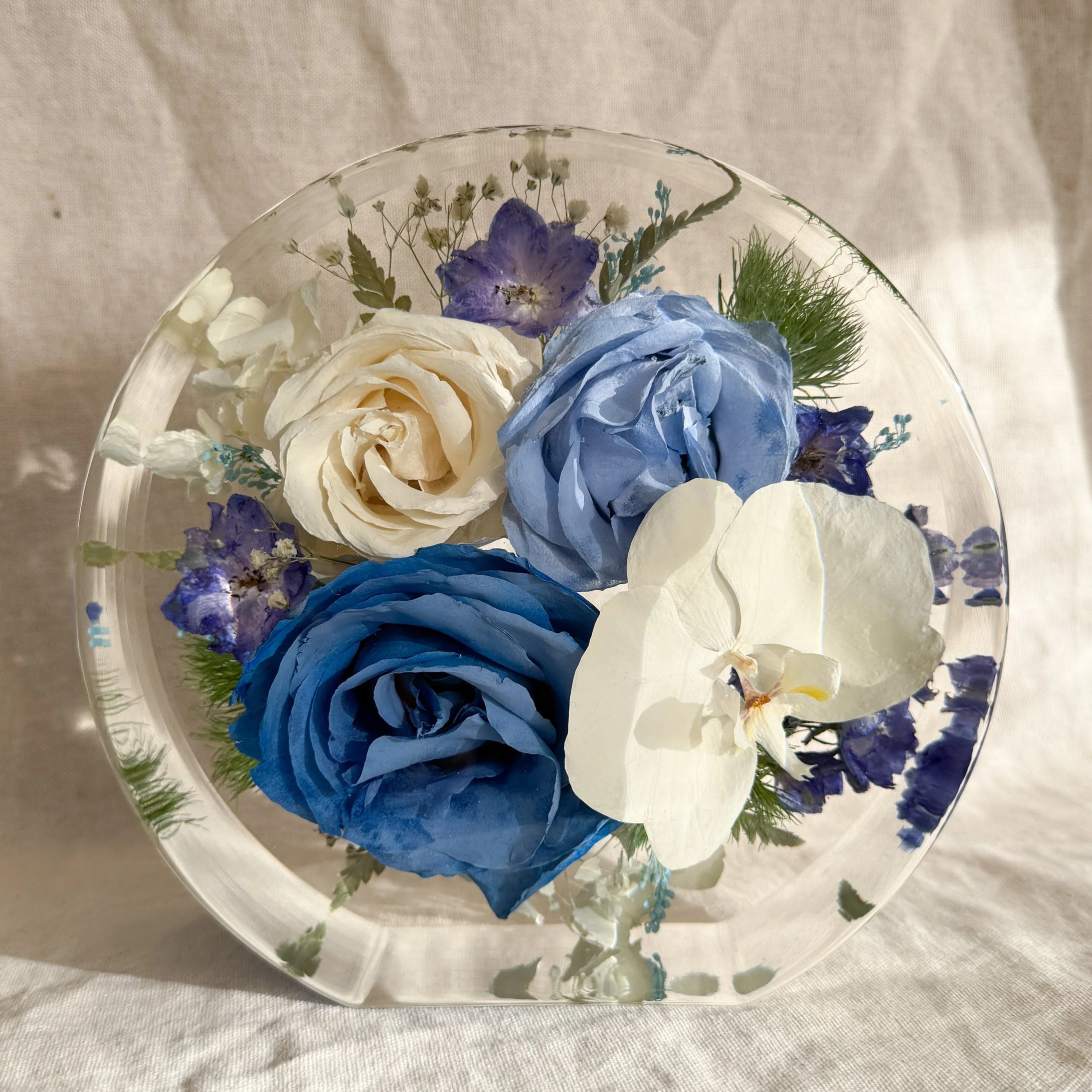 7-inch standing resin circle preserving blue and ivory roses with a white orchid and delicate purple flowers