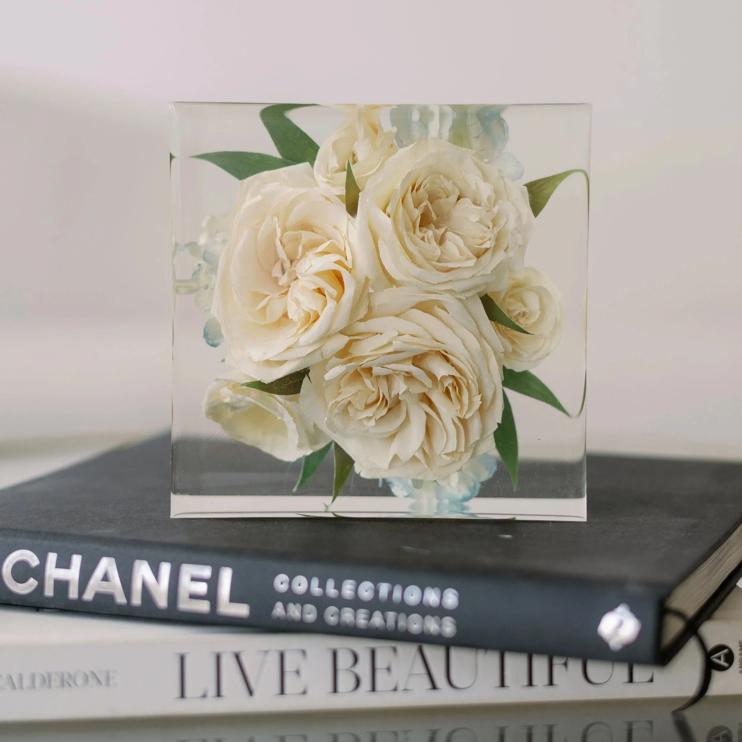 6-inch resin square preserving ivory roses and greenery displayed on a stack of fashion books