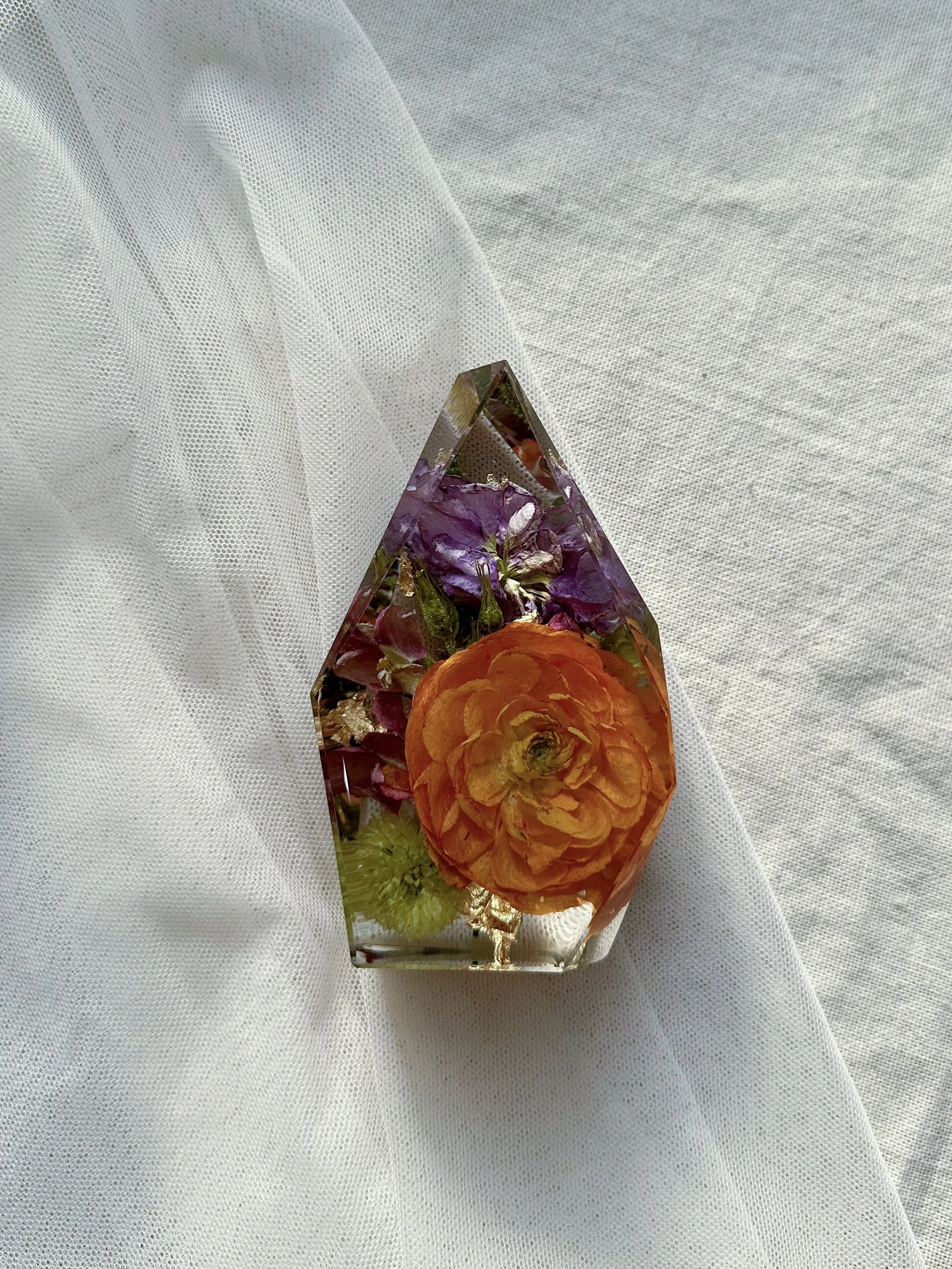 Mini Gem resin keepsake preserving orange, purple, and green flowers from a wedding bouquet