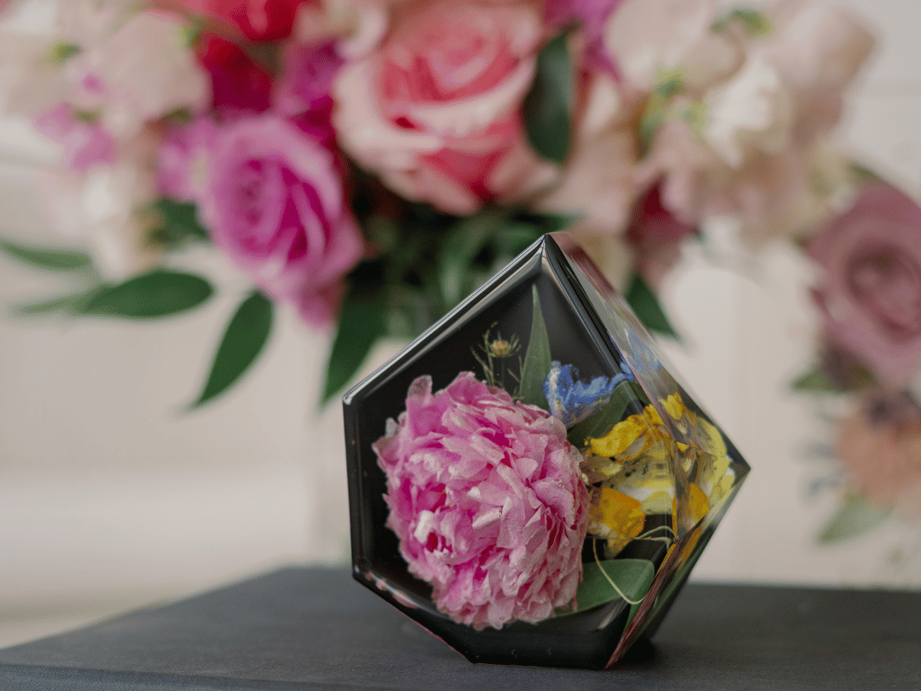 Preserved pink, yellow, and blue flowers in a pentagon-shaped keepsake