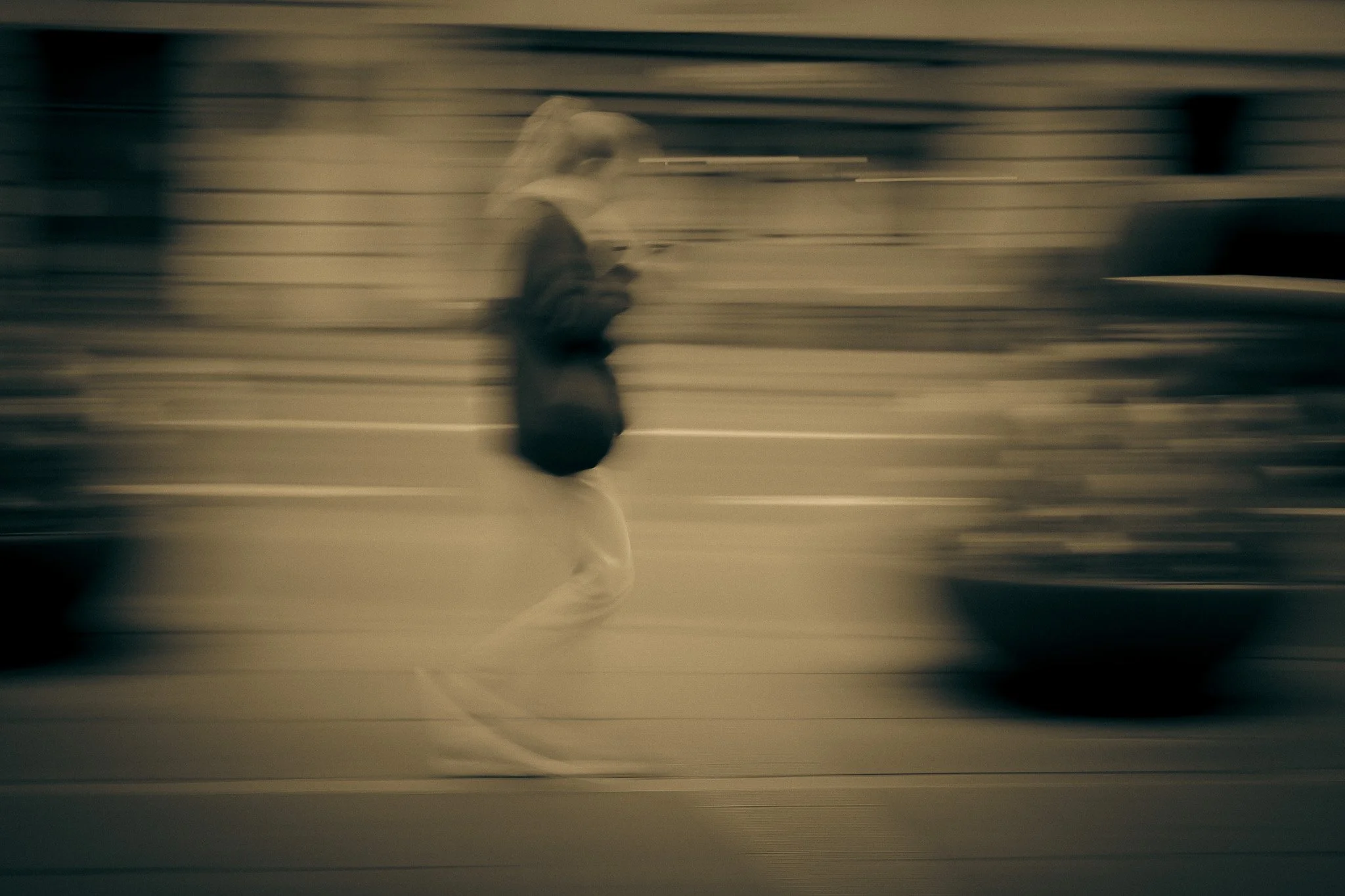 A blurred figure of a person walking while looking at a phone, against a background with horizontal lines, possibly an industrial or urban setting.  THE ART OF PHOTOGRAPHY
