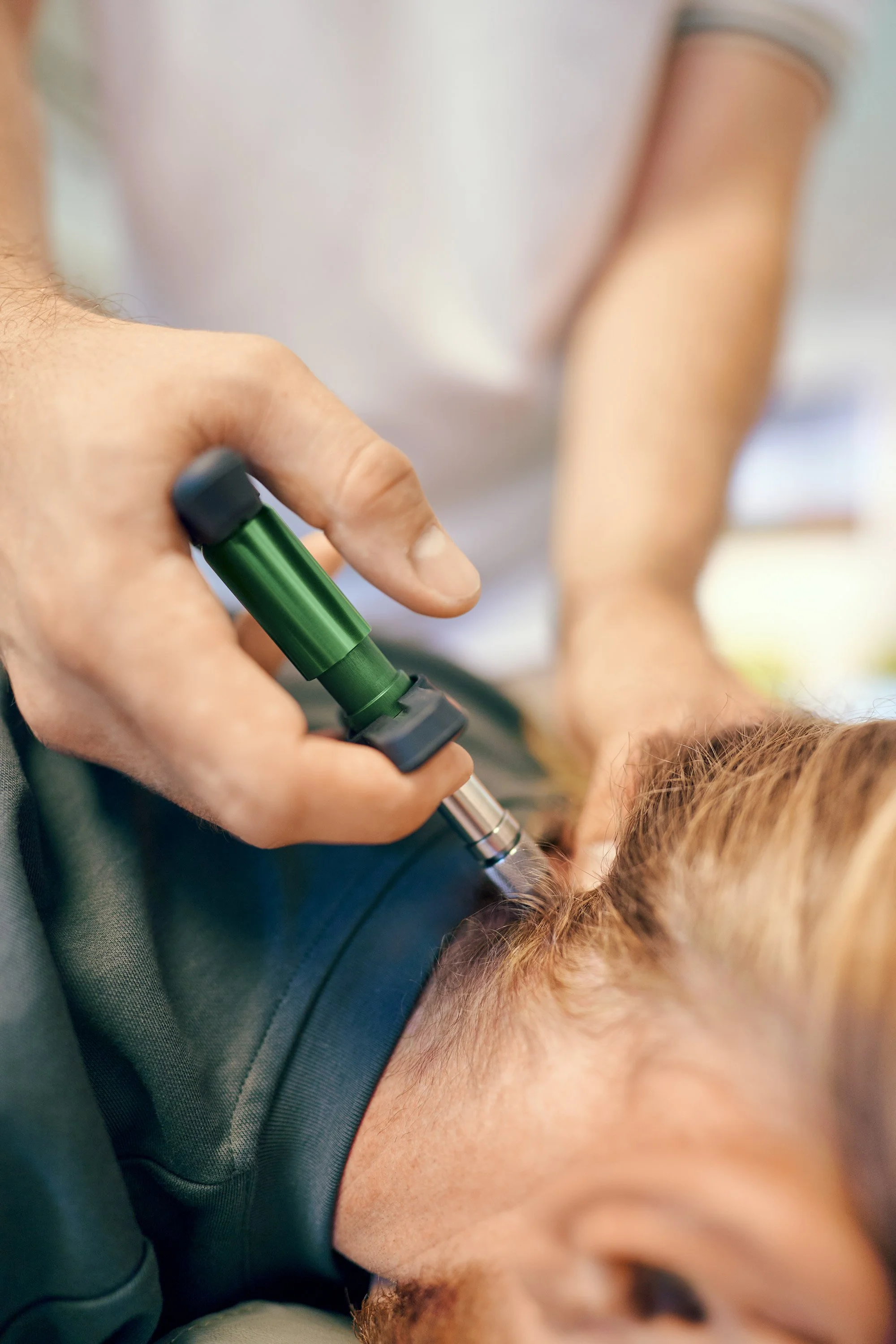 Ein Arzt führt eine Zungenabsaugung bei einem Patienten durch, der auf dem Rücken liegt.
