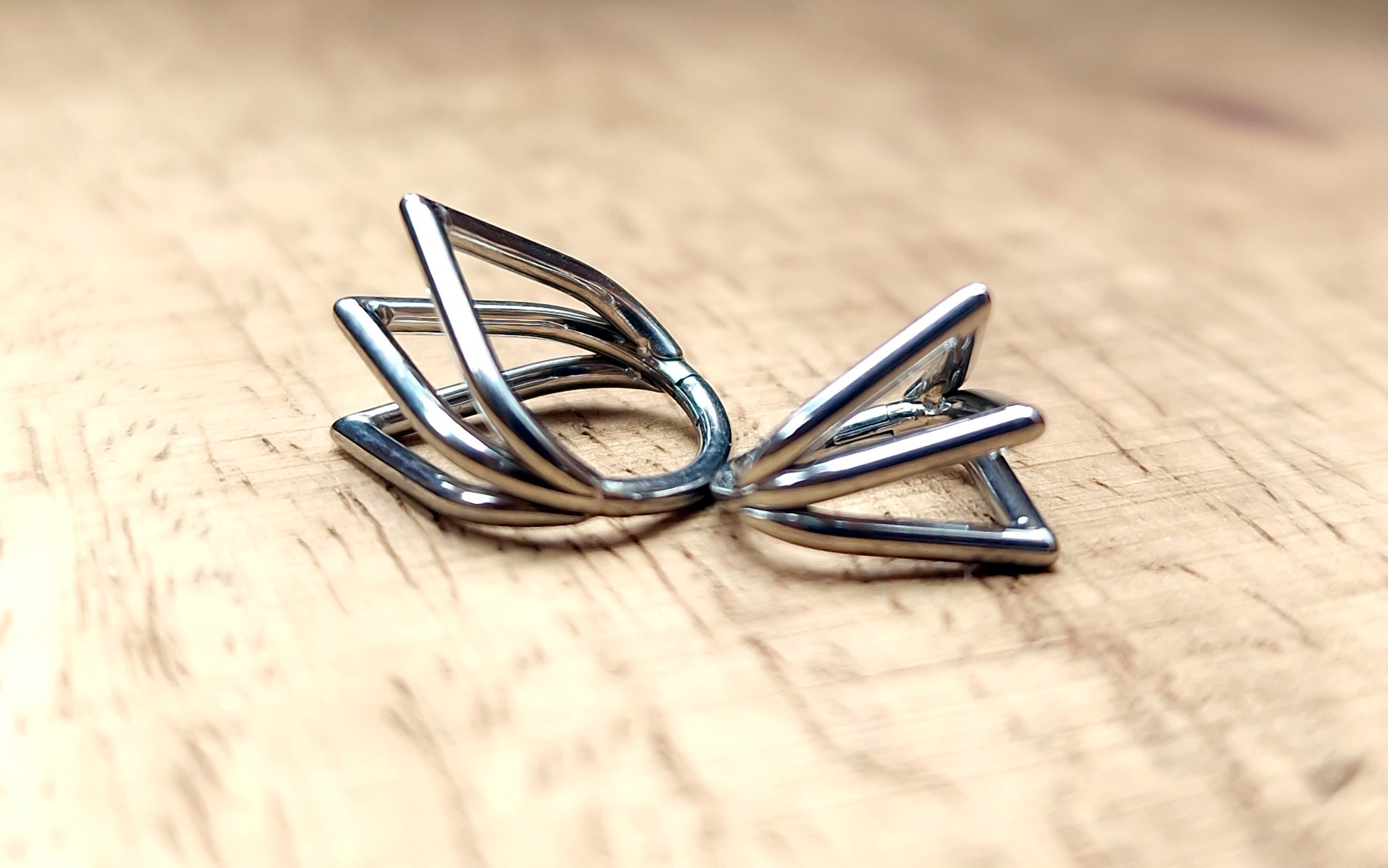 Trine of Thorns, a titanium clicker crowned in triple symmetry, V-shaped piercing jewellery for daith, septum, or cartilage