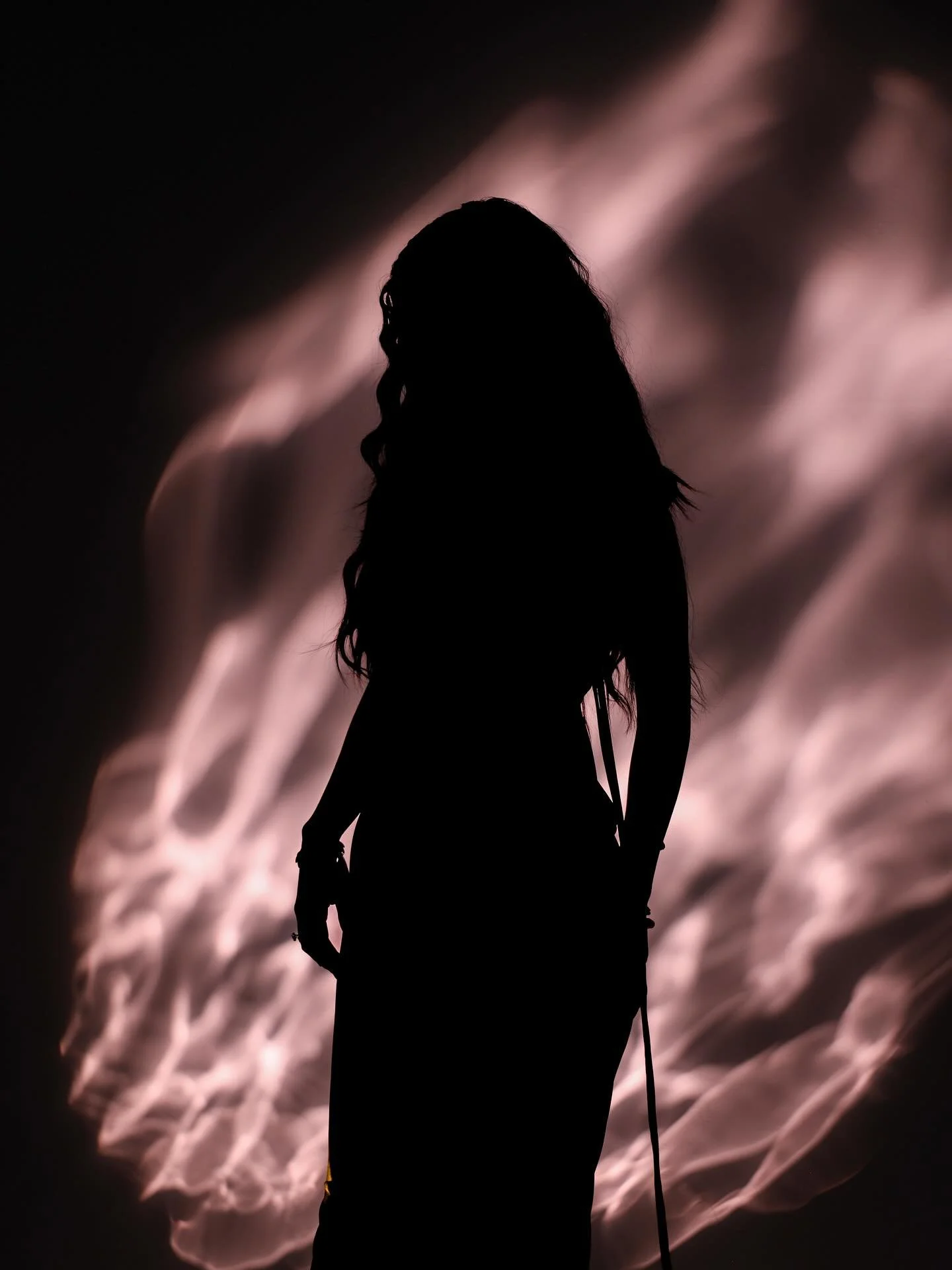 Silhouette of a person standing against a background of glowing, abstract patterns, possibly sparks or fire.